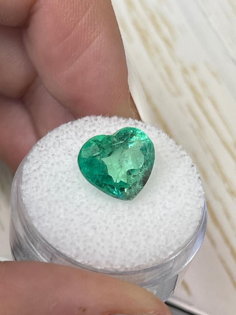 Stone: Emerald
Weight: 5.19-carats
Shape: Heart Cut
Clarity: Transparent
Luster: Very Good
Color: Medium Light Green
Measurements: 12.40mm x 10.38mm x 7.20mm
Geographic Origin: Colombia
Treatment: Natural, Oiling

Comments: Due to their growth
