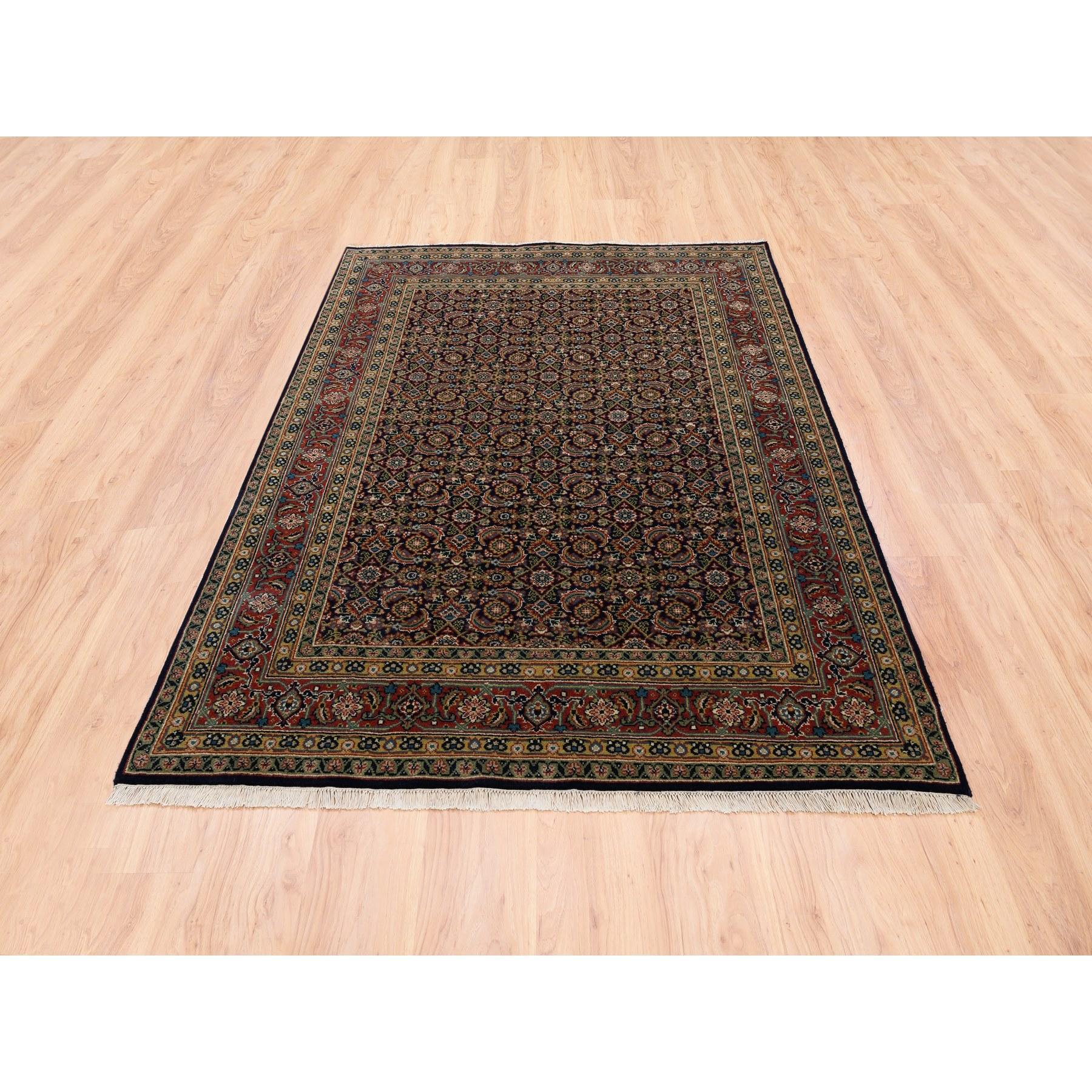 Il s'agit d'un véritable tapis oriental noué à la main, en laine noire filée à la main, avec un motif de poisson d'Herat. Il a été noué pendant des mois et des mois selon les techniques séculaires du tissage persan par des artisans