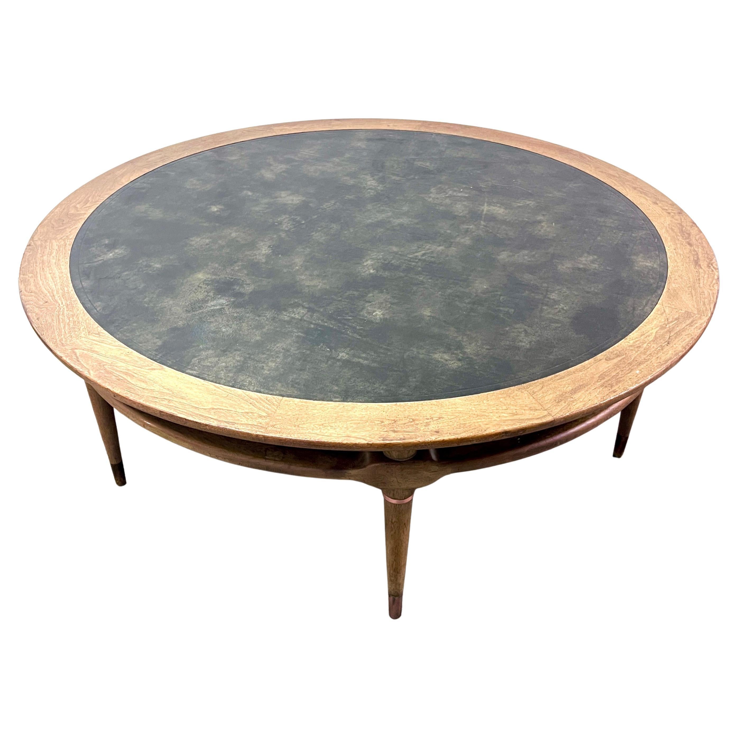 A wonderful and large Round cocktail table with a foil / Black tooled leather top.  The table is a compliment to any room that is in need of a large round table - roomy enough for stacks of books and decor and sturdy enough to also rest your feet