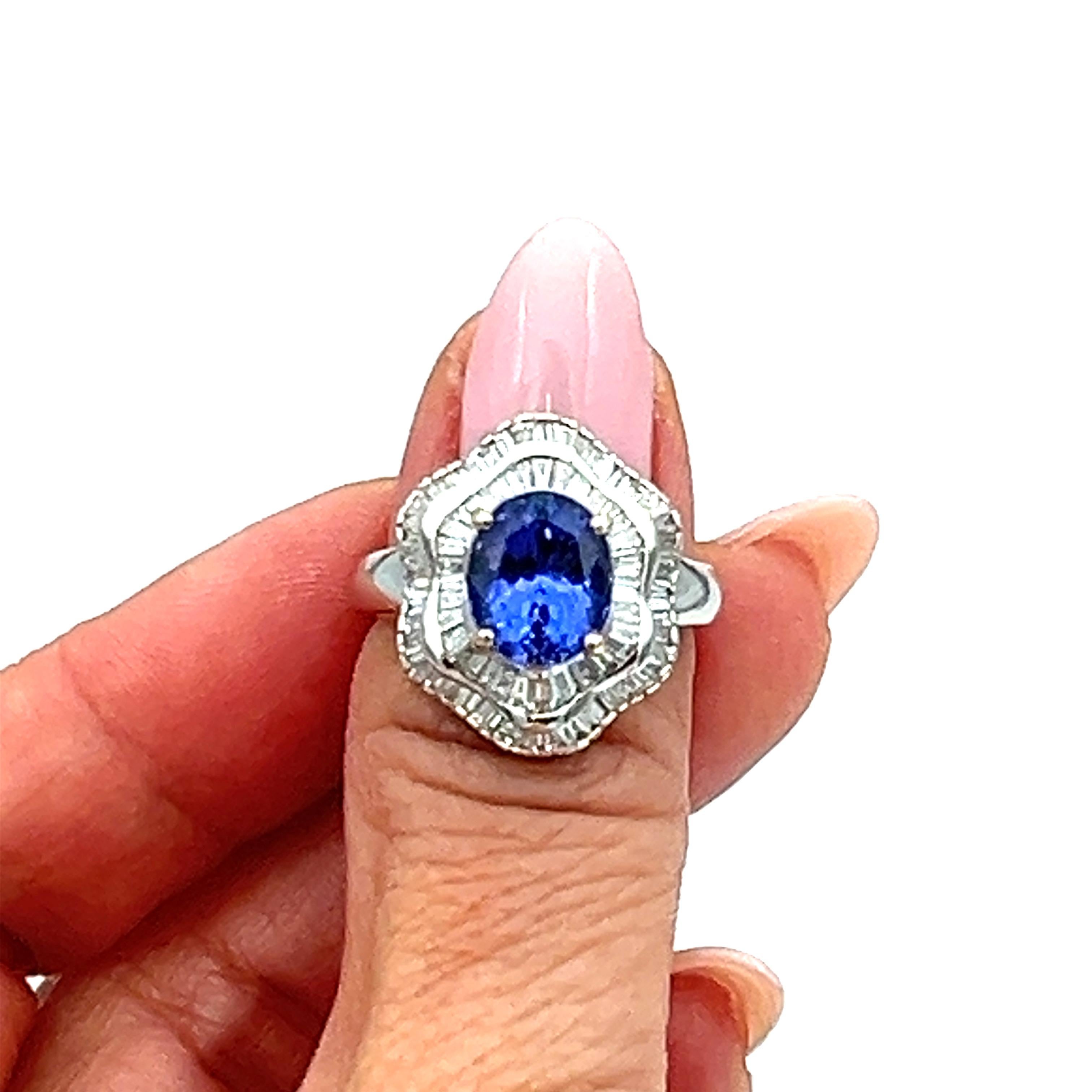 This stunning ring features a 3.11 carat oval-shaped tanzanite stone in a beautiful shade of blue, surrounded by sparkling white diamonds. The ring is made of 18k white gold and has a ring size of 7. The gemstones are set in a way that allows for