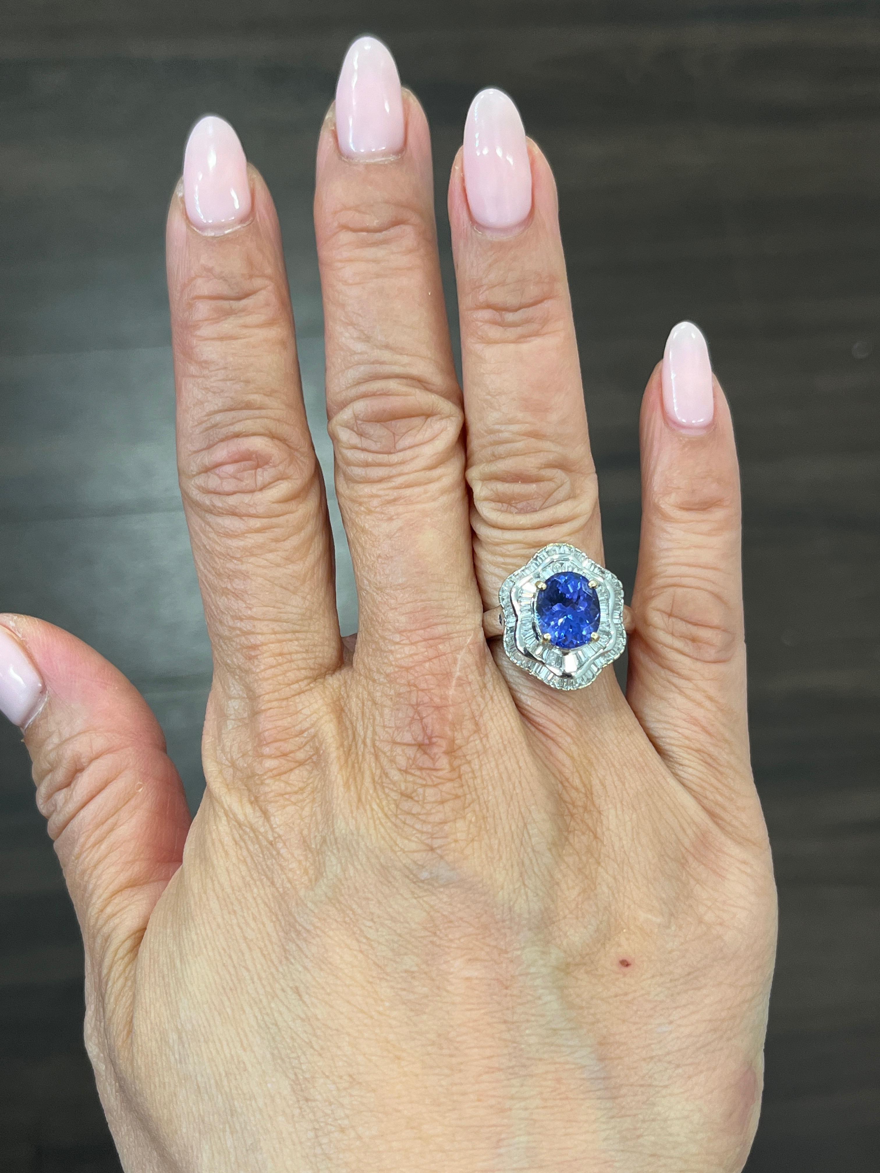 This stunning ring features a 3.11 carat oval-shaped tanzanite stone in a beautiful shade of blue, surrounded by sparkling white diamonds. The ring is made of 18k white gold and has a ring size of 7. The gemstones are set in a way that allows for
