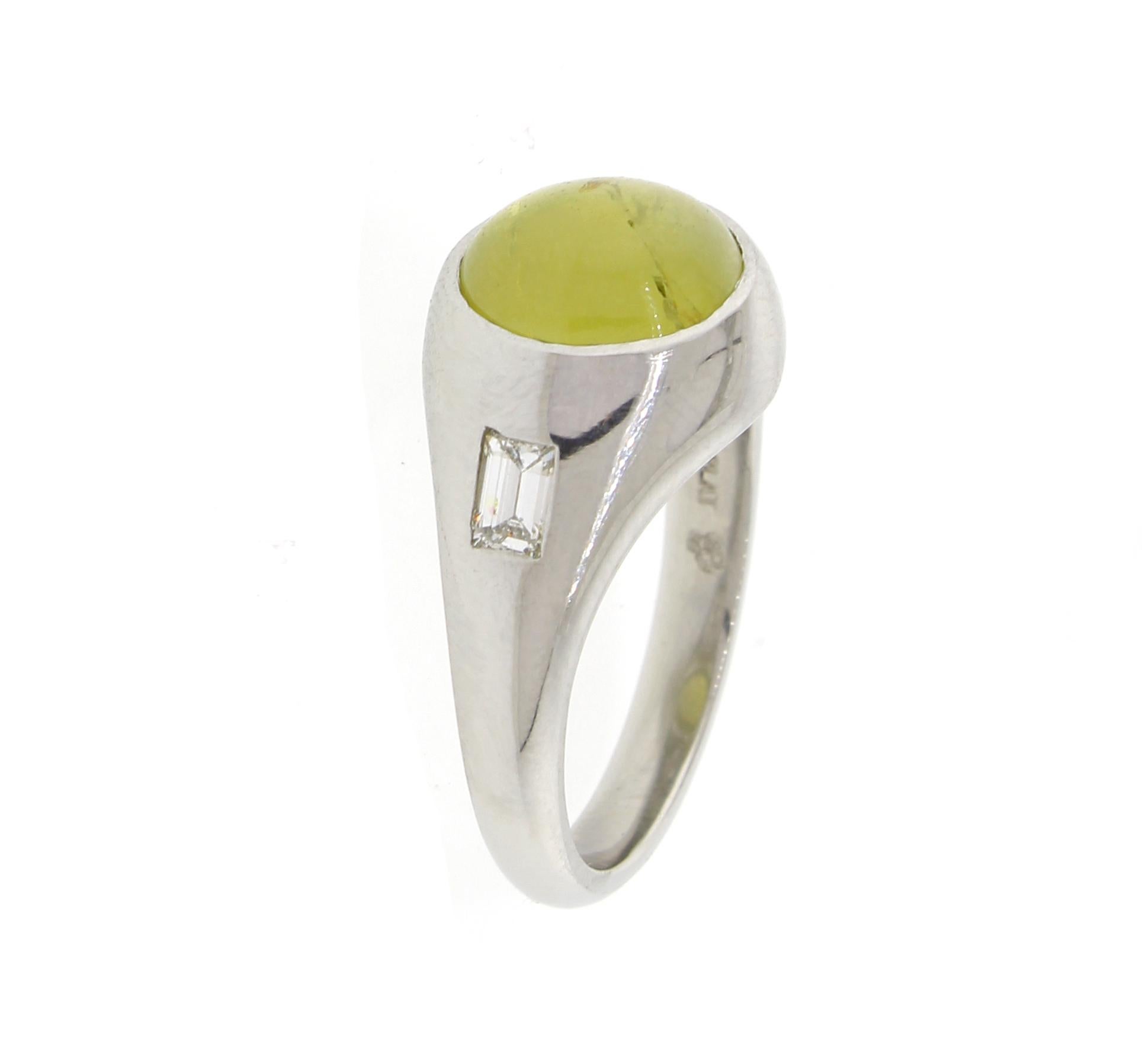 A green and honey  natural Chrysoberyl with a strong cat's eye is set in a platinum gypsy setting with two diamonds weighing .46 carats. The eye opens a closes cleanly, slightly included.