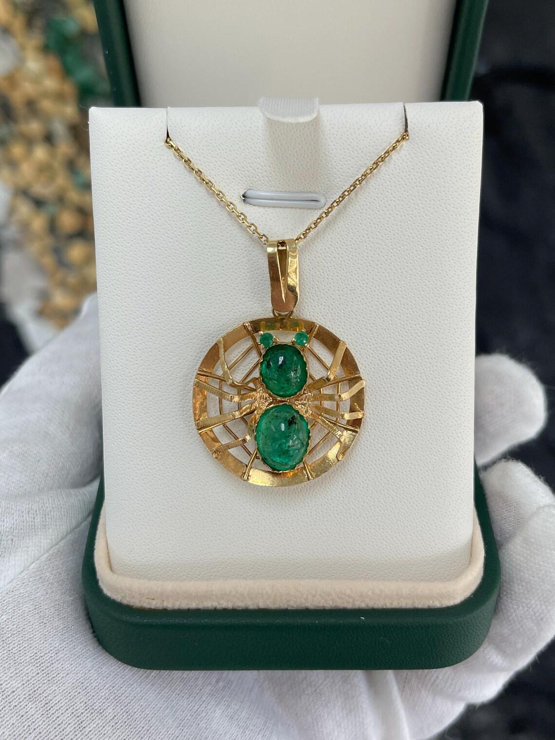 Ce pendentif personnalisé unique est un véritable chef-d'œuvre, conçu de manière complexe pour ressembler à une magnifique araignée en or jaune 18 carats et en émeraudes colombiennes éclatantes. Le corps de l'araignée est orné de superbes émeraudes