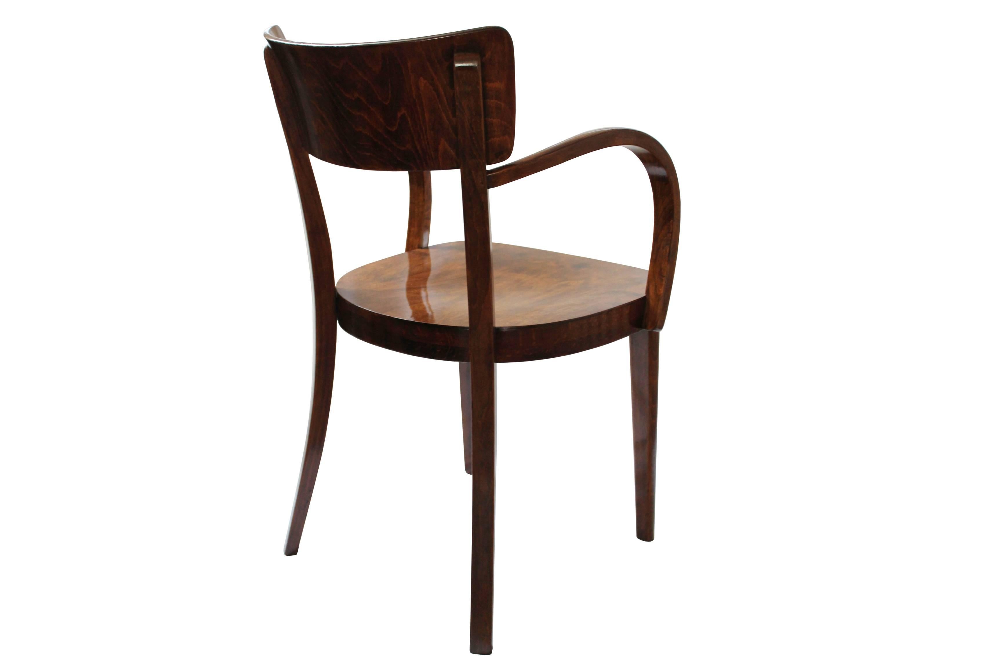 A rare bentwood dining chair with a unique shape of arms and particularly beautiful veneered pattern on the seat, both arms as well as the backrest, was designed and made by Thonet Mundus in 1934.
The frame has been strengthened in a recent