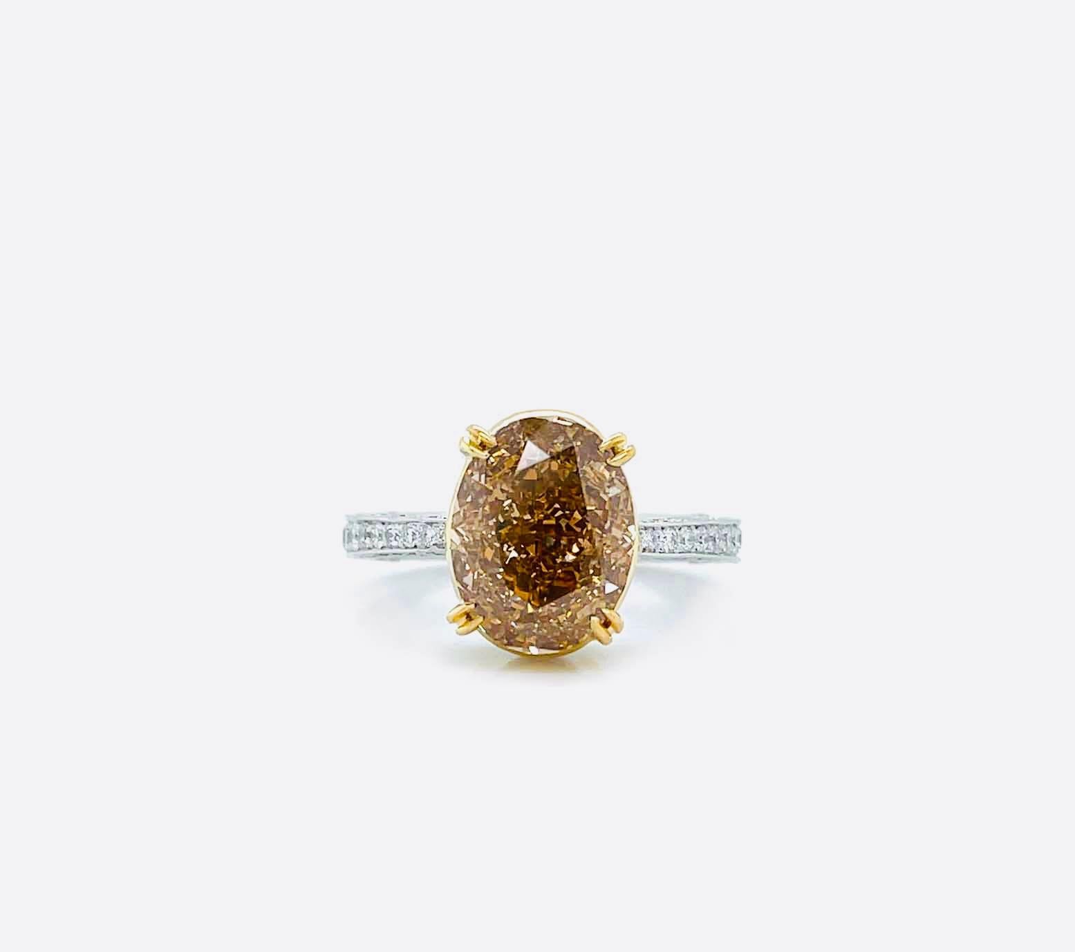 Bague de fiançailles intemporelle en diamant Fancy Brown Orange de 5,25 carats de taille ovale, certifiée par le GIA avec un degré de pureté I1. Le design Eleg met en valeur la beauté de la pierre centrale, complétée par 116 diamants blancs ronds et