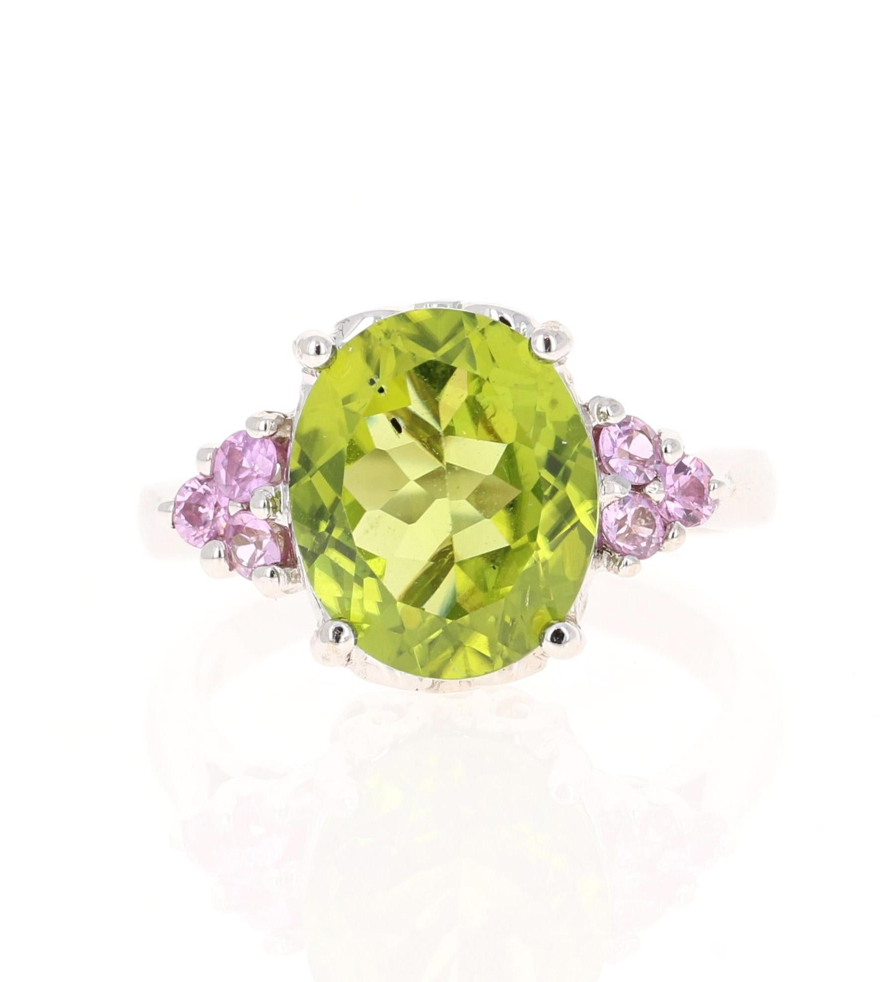 This beautiful ring has an Oval Cut Peridot that weighs 4.88 Carats. The ring is surrounded by 6 Pink Sapphires that weigh 0.37 Carats. The total carat weight of this ring is 5.25 Carats. 

Curated in 14 Karat White Gold and weighs approximately 5.2