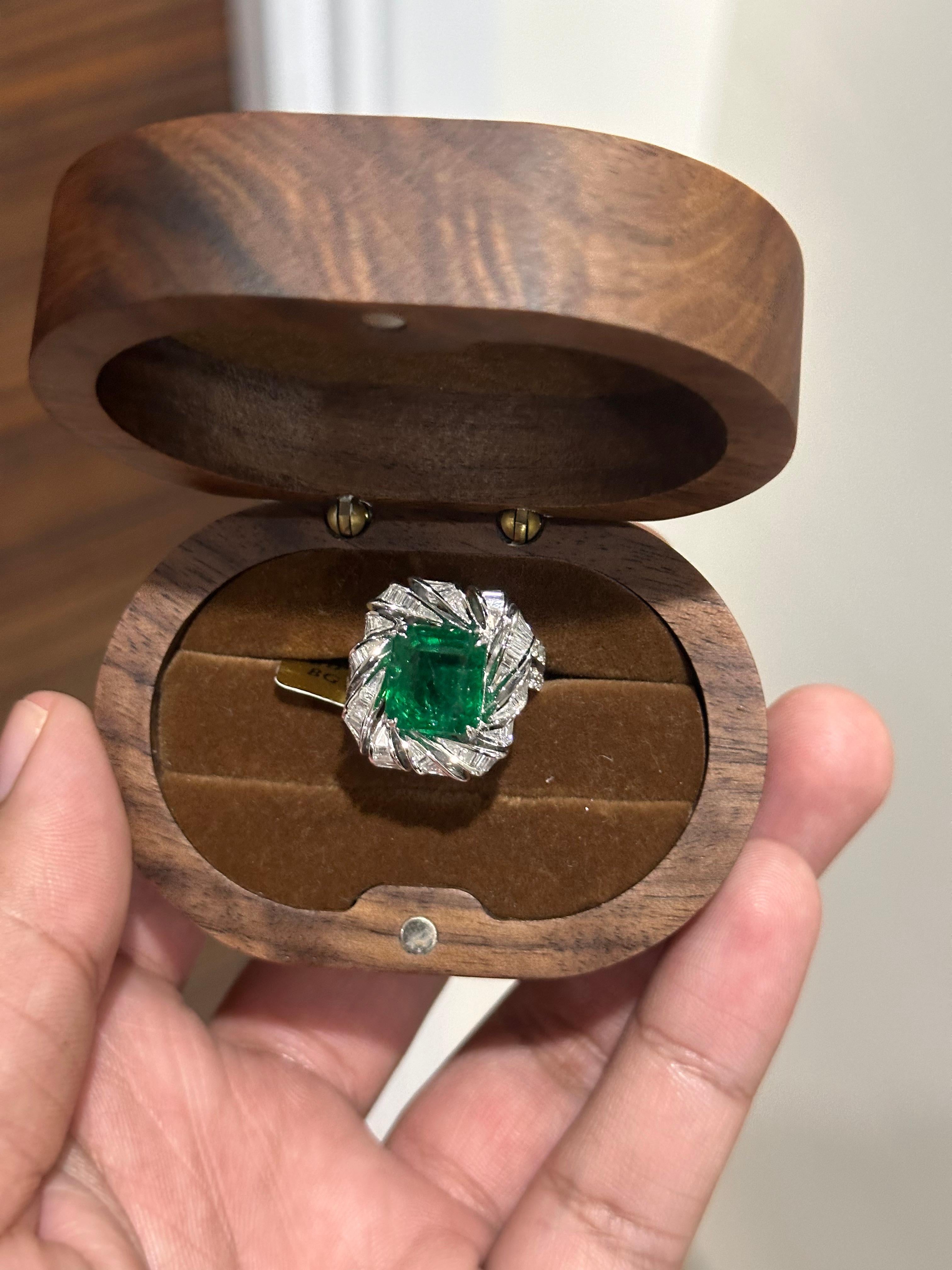 A masterful blend of sophistication and bold beauty, this exquisite ring is centered around a striking 5.25 carat natural Zambian emerald, known for its rich, saturated green hue and exceptional clarity. The emerald has undergone minor oil