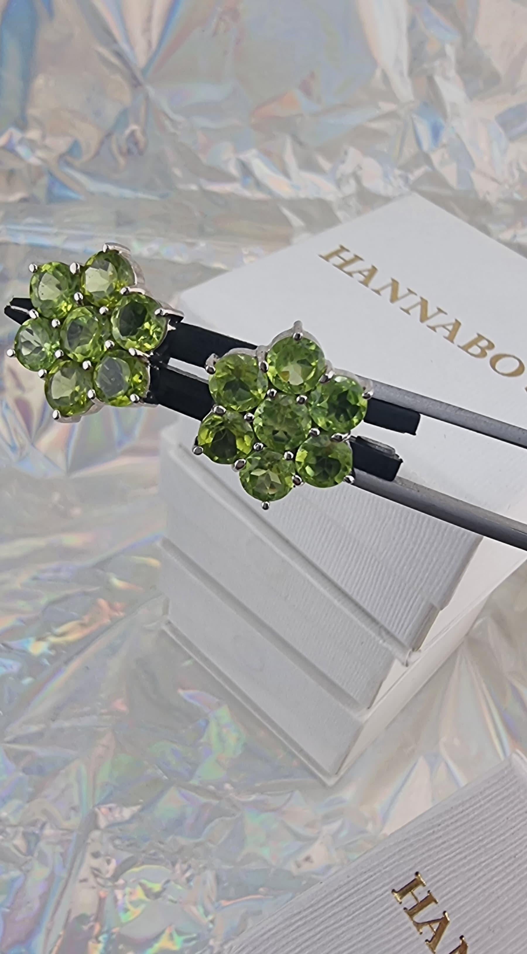 Estos pendientes de peridoto verde menta en plata de ley recubierta de platino son un complemento delicado y encantador para tu colección de joyas. 
Estos pendientes presentan siete brillantes gemas de peridoto de talla redonda, de 0,75 quilates