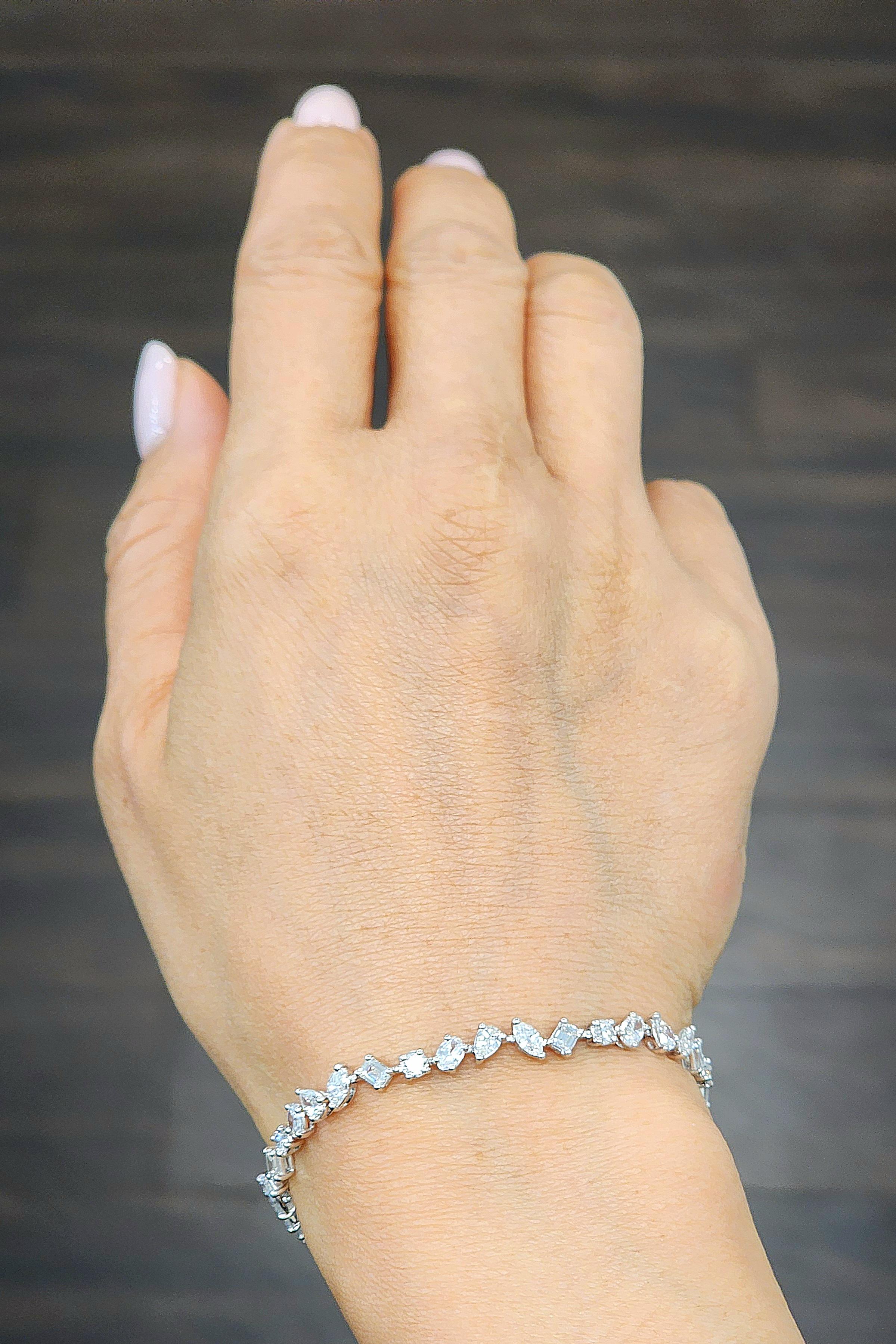 Ce magnifique bracelet de tennis en diamants de formes variées présente des ronds, des marquis, des poires, des émeraudes et des ovales. Le bracelet comporte 40 diamants de couleur E/F et de pureté VS.