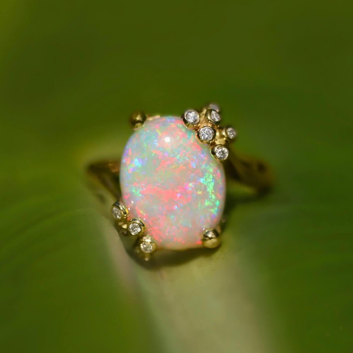 A beautiful floral-pattern light opal set in a unique handcrafted floral setting, displaying 11 brilliant white diamonds and a seedpod back showing its full colours on all sides. Fit for a princess, the opal sits proudly high and as flashes pinks,