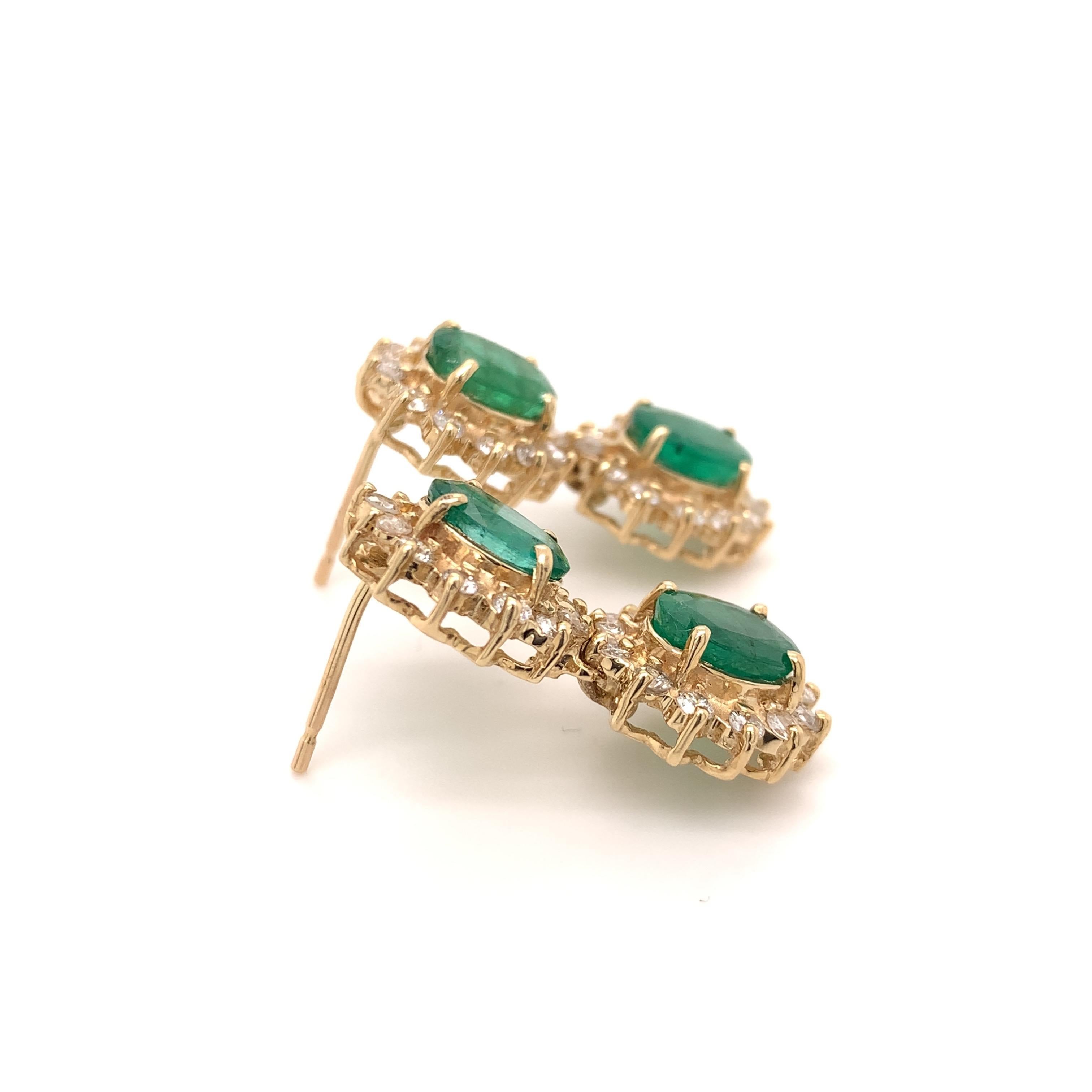 Radiant emerald dangling earrings. High brilliance, lively green tone, oval faceted, 5.29 carats natural emeralds encased in open profile mounting with four bead prongs each, accented with round brilliant cut diamonds. Handcrafted contemporary