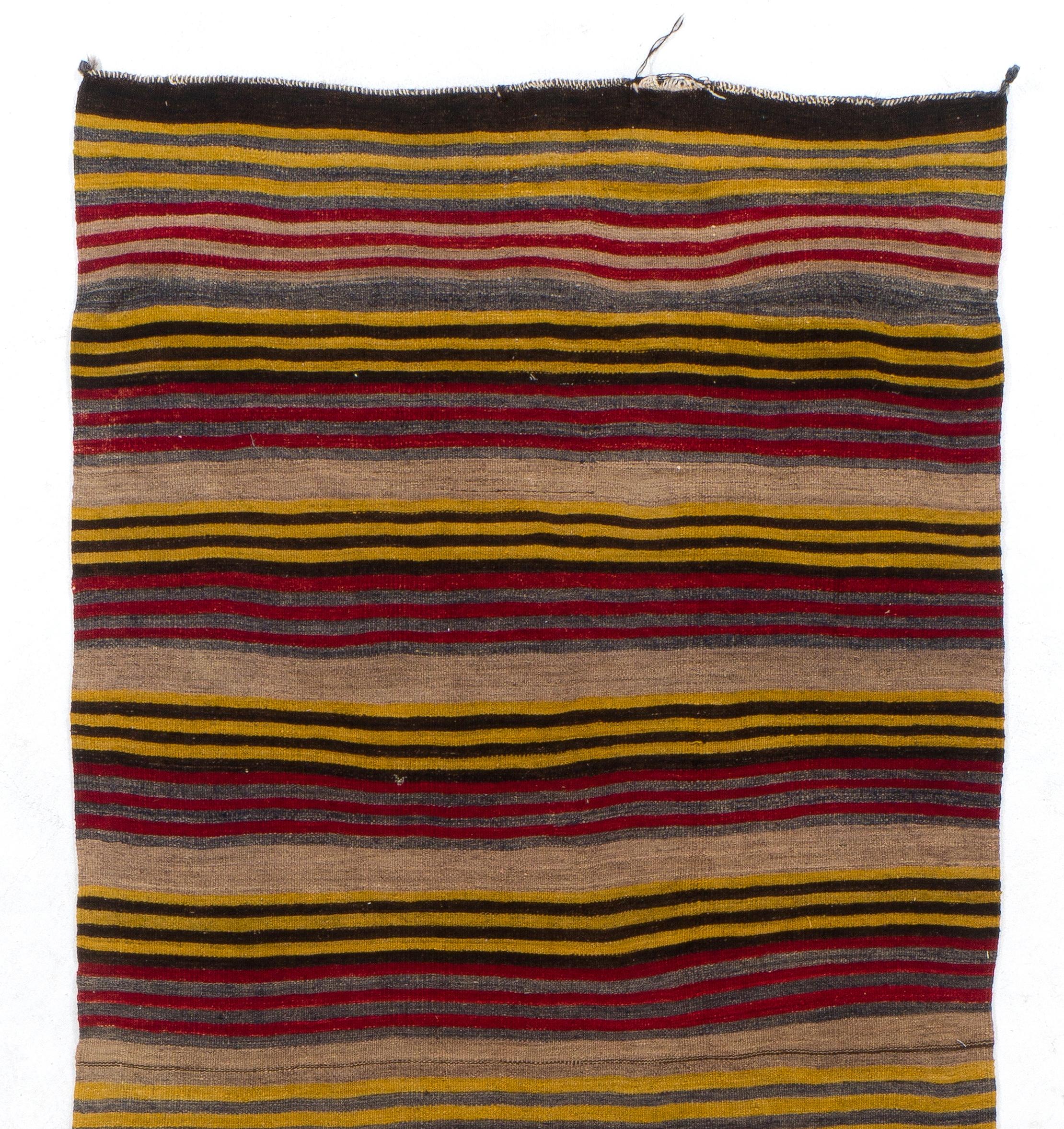 A simple yet beautiful wool kilim/flat-weave handwoven by the nomadic tribes in the 1960s in South Central Turkey with a striped design in ruby red, oatmeal, faded blue, mustard yellow and dark brown. The kilim was handwoven with fine hand-spun
