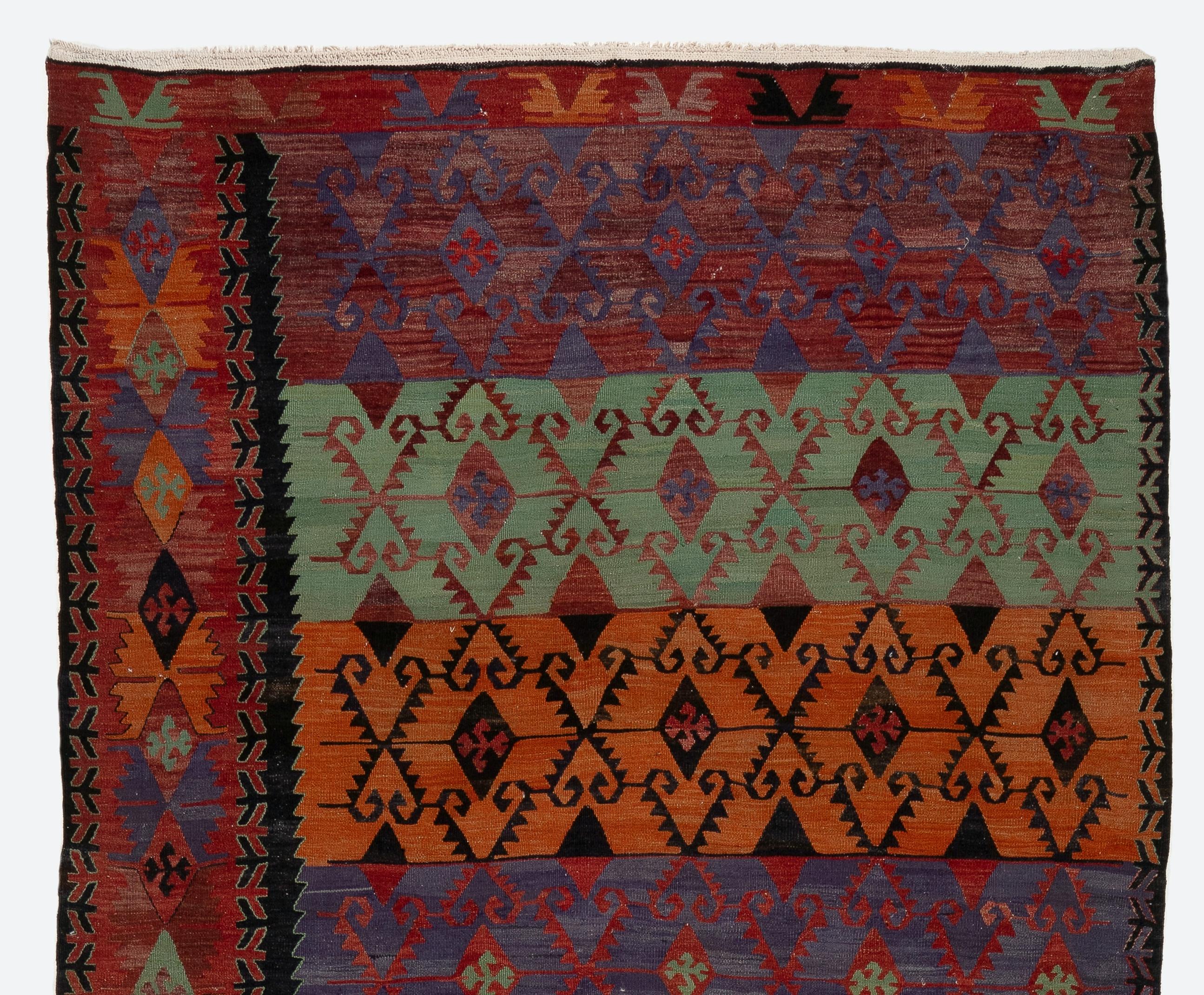 Un raro tappeto vintage tessuto a mano a trama piatta (kilim) proveniente dalla Turchia con un design e una storia di colori insoliti. È caratterizzato da un'unica colonna di bordo che attraversa tutta la lunghezza del tappeto in un bellissimo rosso