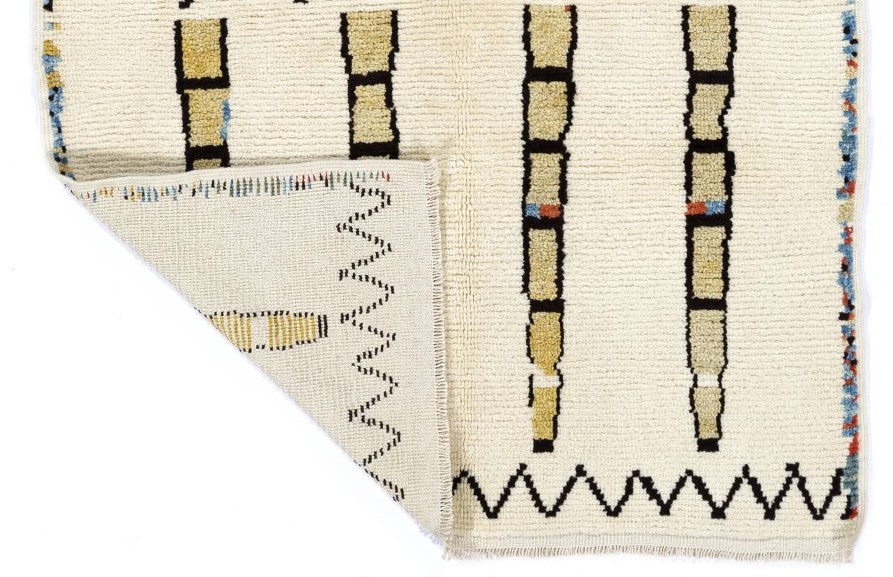 A modern hand-knotted Moroccan rug featuring a quirky minimalist design, made of natural un-dyed ivory and brown wool with hints of colored wool in places. It has soft, thick pile that feels very comfortable under feet. 

Size: 5.2 x 8.3
