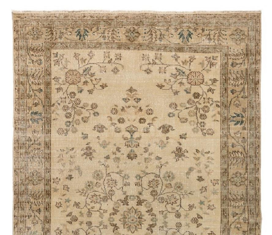 A vintage handmade Turkish area rug with a dainty floral design in beige, brown and touches of faded green in places. The rug has low wool pile on cotton foundation. It is in good condition, professionally-washed, sturdy and suitable for areas with