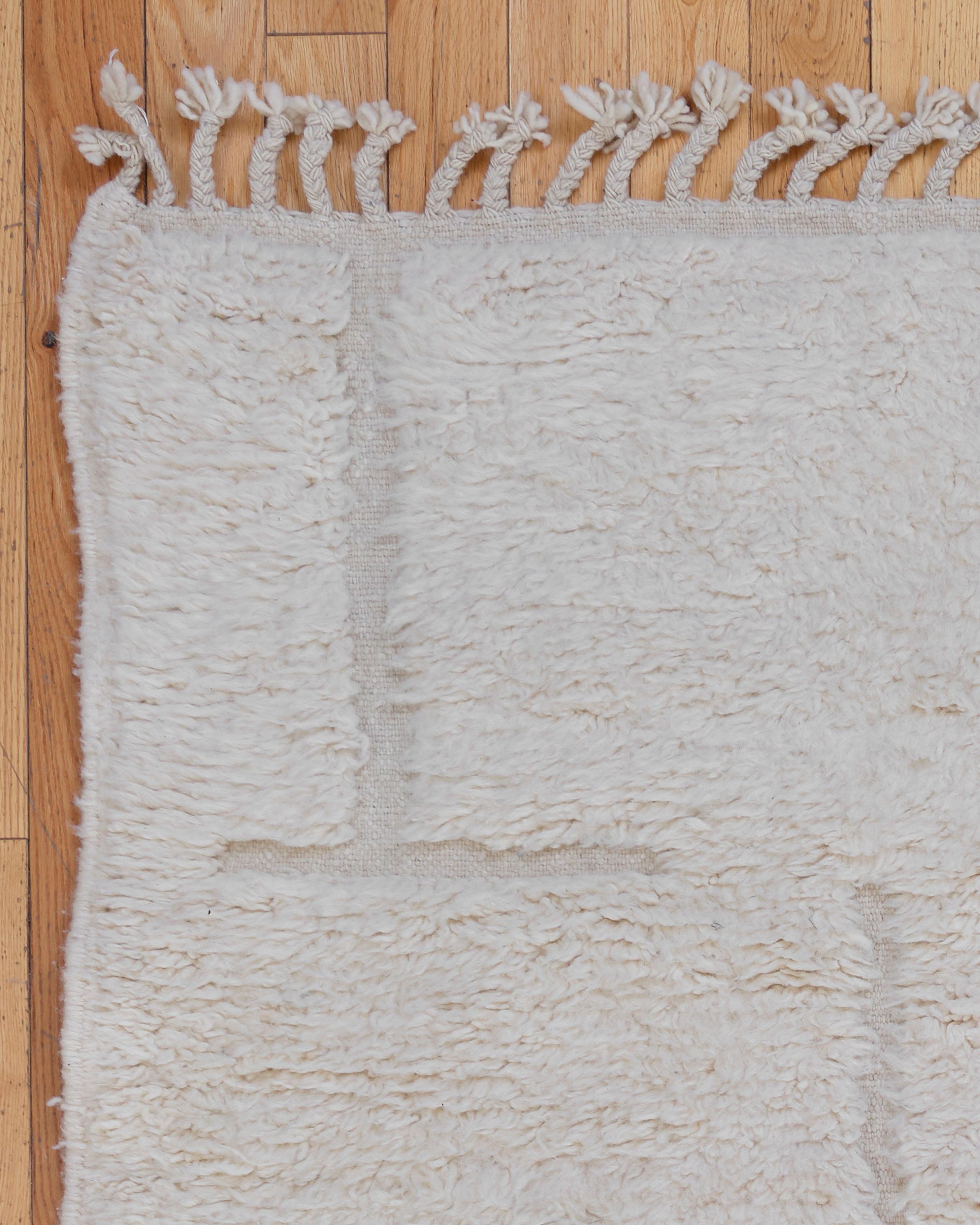 The Foxglove rug is a beautiful Beni Ouarain piece, handwoven by Berber artisans in the Atlas Mountains of Morocco. Featuring a soft cream background, this rug showcases intricate, minimalist geometric patterns, a hallmark of traditional Beni