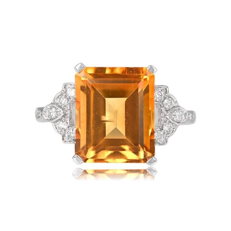 An 18k white gold ring showcases a 5.30-carat emerald-cut citrine, elegantly set in prongs. The citrine is complemented by a geometric design adorned with round brilliant diamonds. Additional diamonds grace the shoulders, and the under-gallery