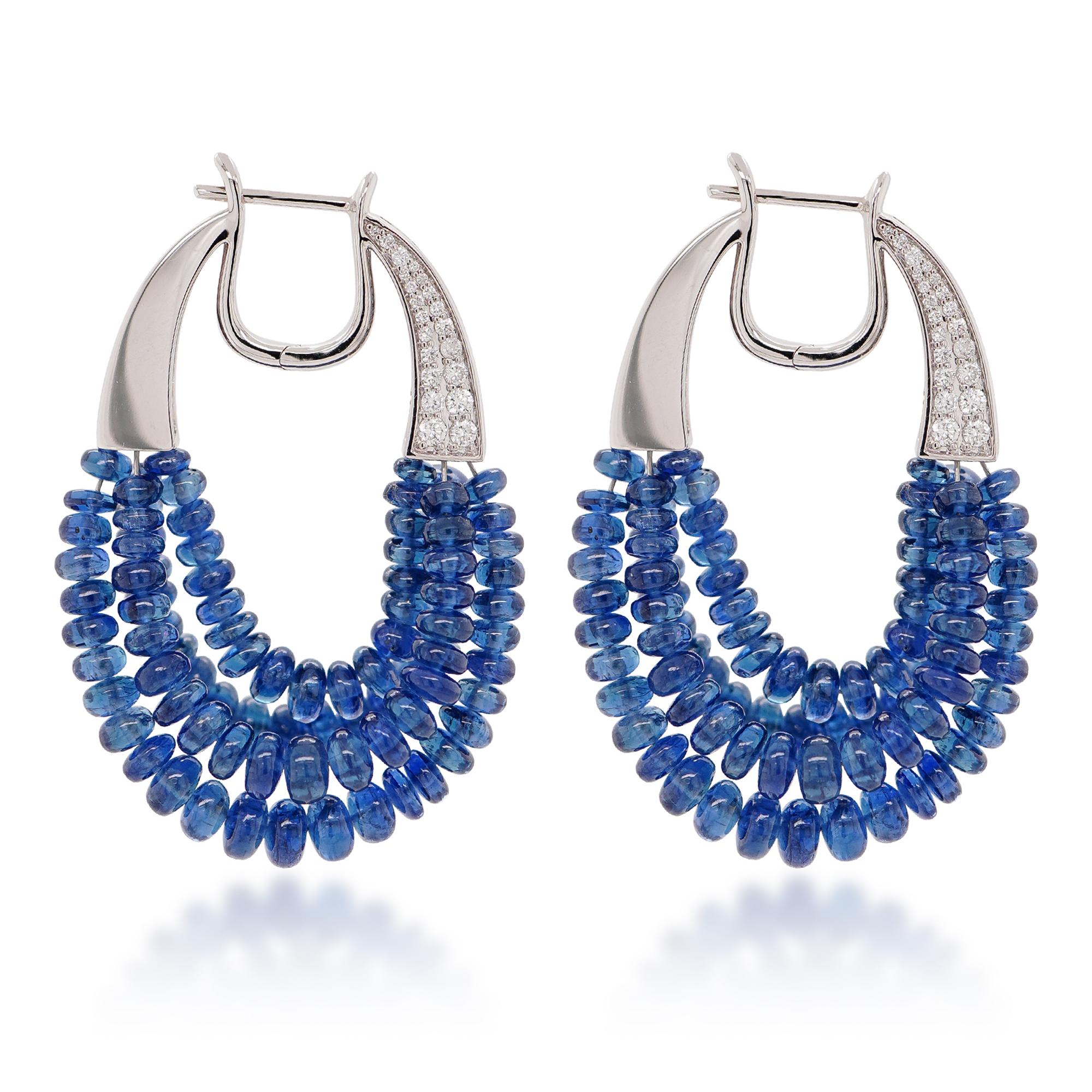 These exquisite earrings command attention with their vibrant centerpiece: a pair of 53.19-carat vivid blue sapphires. The intense saturation and brilliance of these gems evoke the depths of a tropical ocean, capturing and reflecting light with