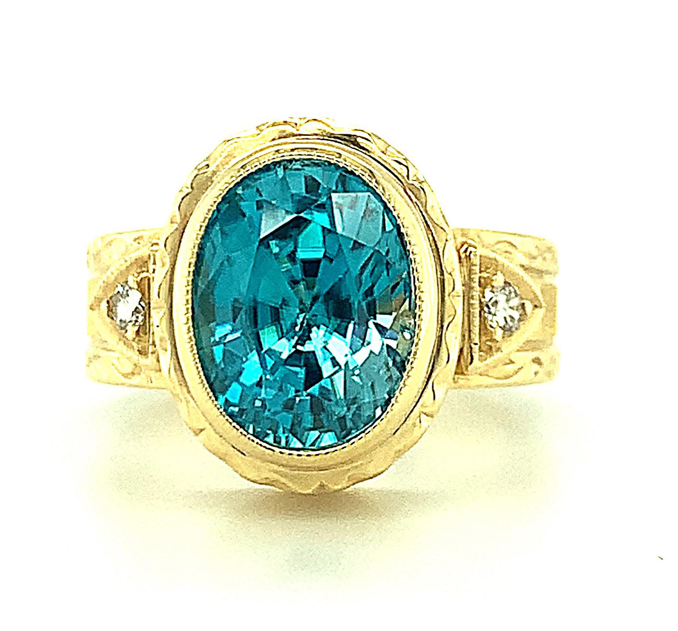 This stunning 5.34 carat blue zircon displays brilliant color and its fine quality is well-matched by the exquisite  craftsmanship of this handmade ring. The 18k yellow gold bezel showcasing the center stone and the diamond studded band have both