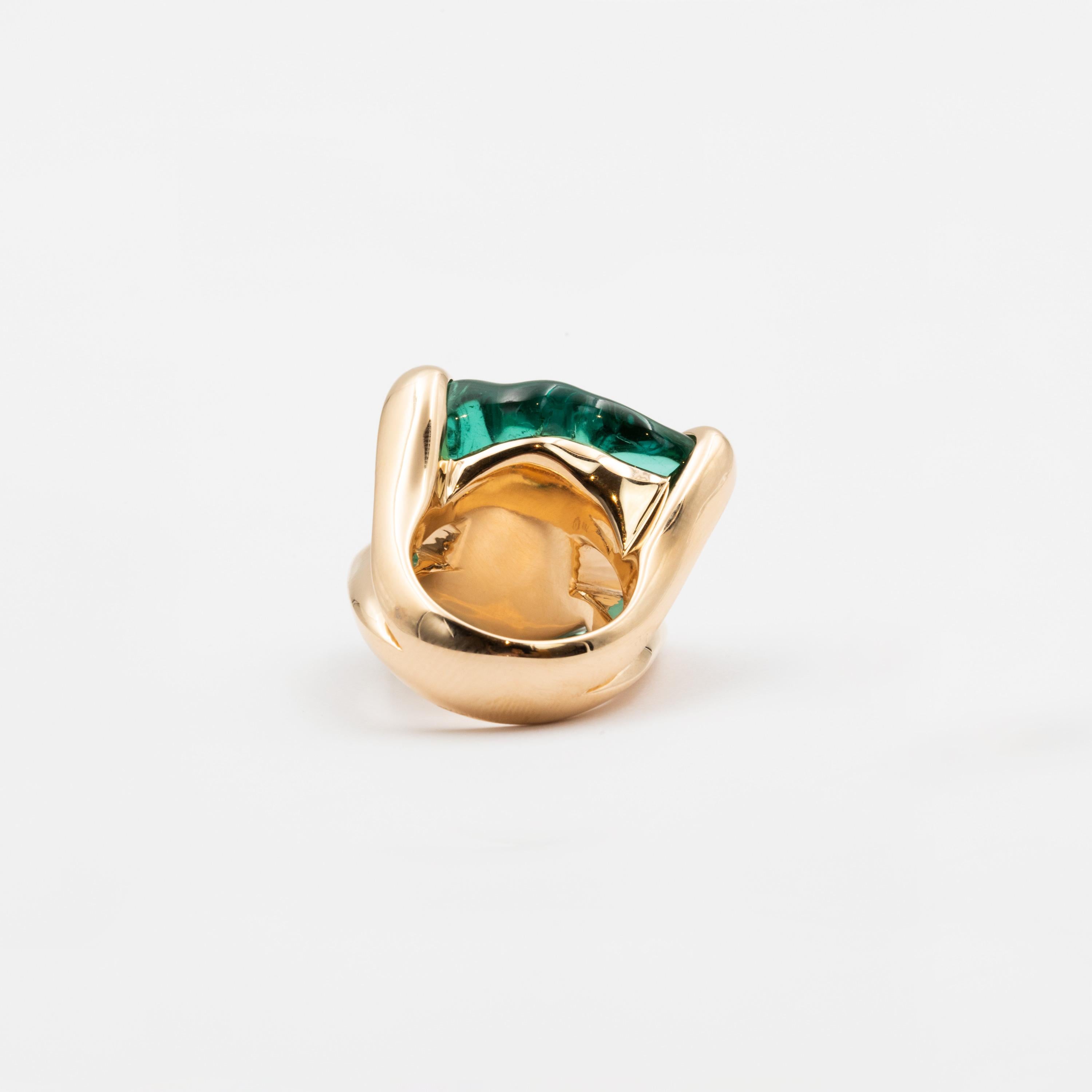 This 53.49 carat Tourmaline of an intense deep green color is the centerpiece of this extraordinary ring. The baroque-cut stone’s undulating shape reminds of vivid waves and catches the eye with its hypnotizing color. Imitating the precious