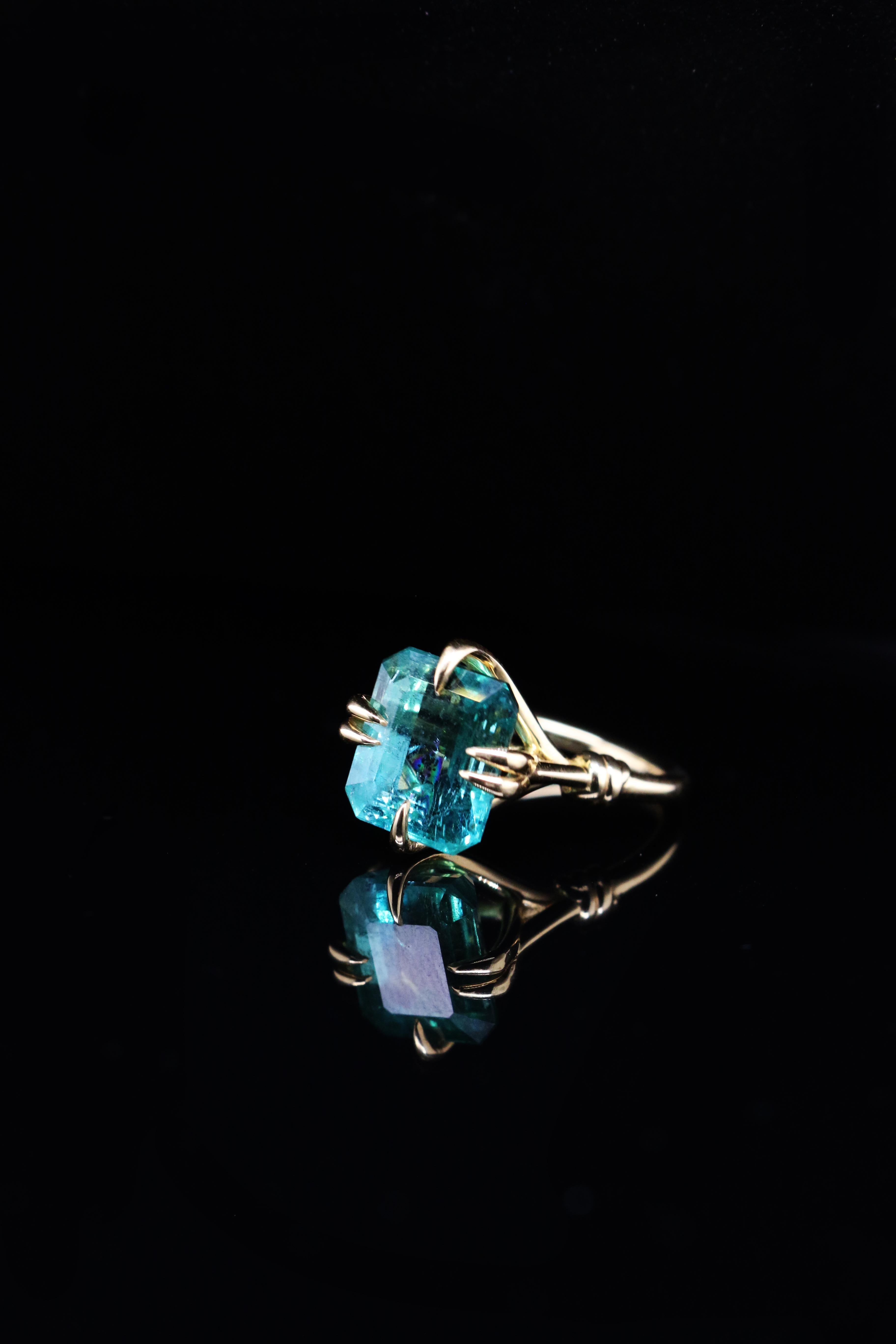 Une audace glamour et une séduction sans faille. Cette bague est ornée d'une émeraude zambienne de 5,35 carats.  Le poisson est posé entre les serres acérées d'un aigle et enlacé par de puissantes cordes nouées de récifs dorés.

Fabriqué à la main