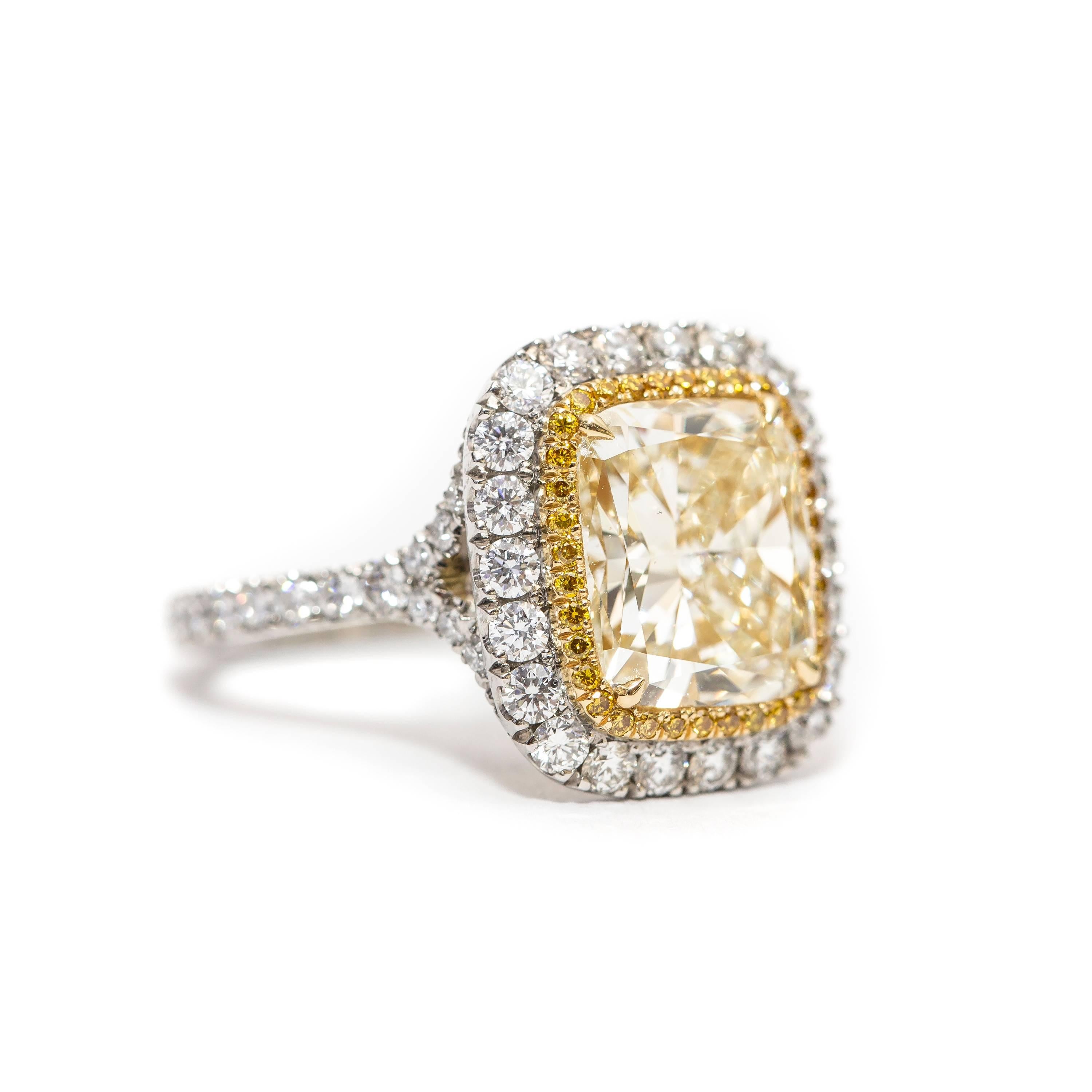 This Spectacular Yellow 4.23 Carat Radiant cut Diamond (Color W-X) which is set in the center with 0.14 Carat of Round Brilliant cut Fancy Intense Yellow Diamonds on the perimeter with 1.14 Carat Color H Clarity SI1 of Round Brilliant Diamonds on