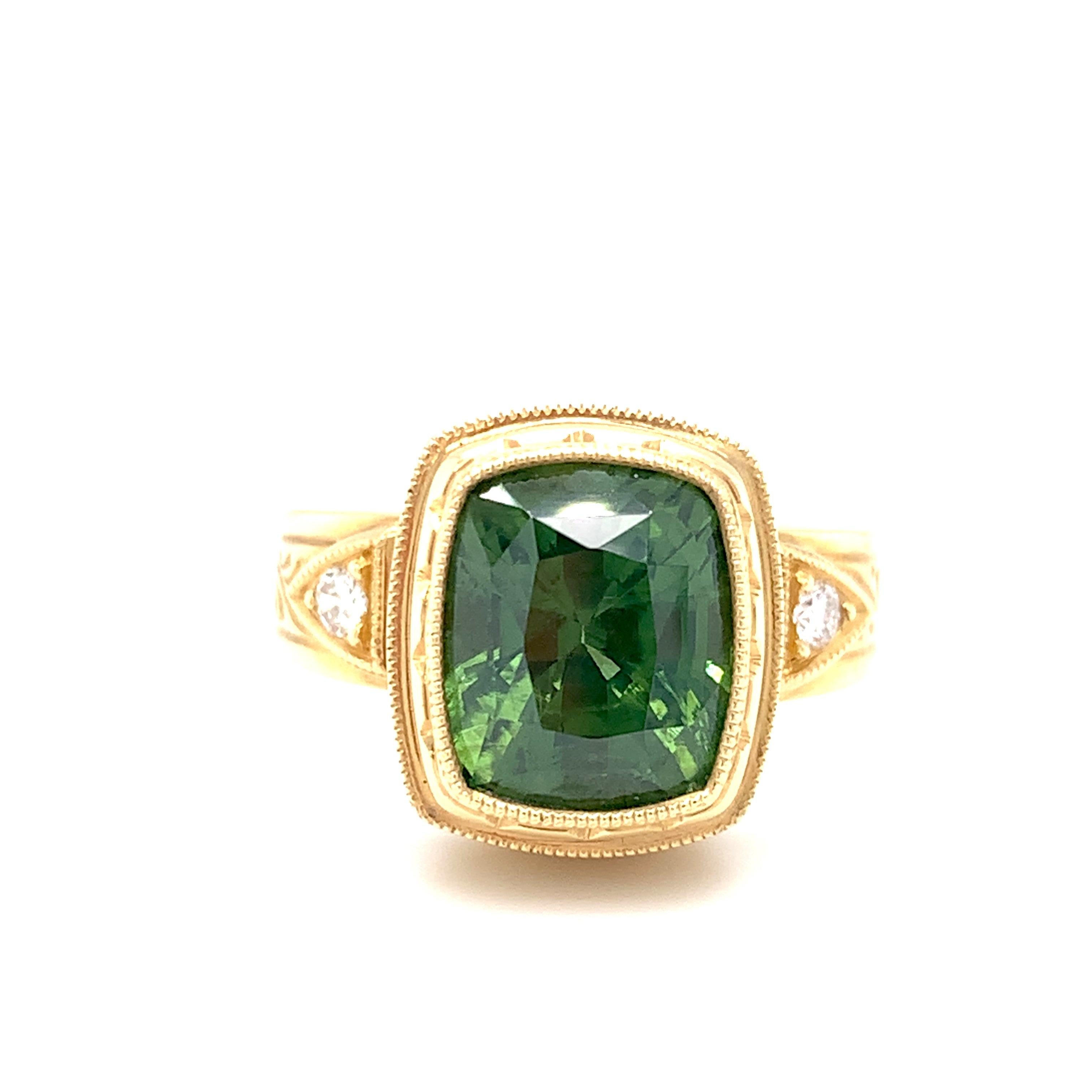 This beautifully handmade ring features a 5.38 carat green zircon set in an intricately hand engraved 18k yellow gold bezel. Two brilliant cut white diamonds add sparkle to this design, which is one of our signature favorites. Zircon occurs in a