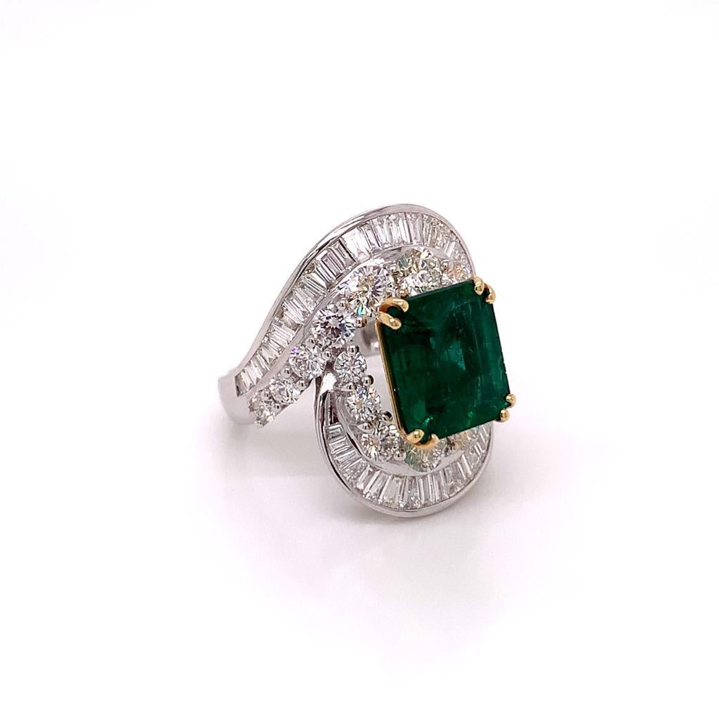 This distinctive ring features a phenomenal 5.39 Carat emerald cut Emerald at its centre, surrounded by a unique arrangement of round brilliant and tapered baguette cut diamonds. The diamonds in this ring weigh a total of 4.03 carats and are set in