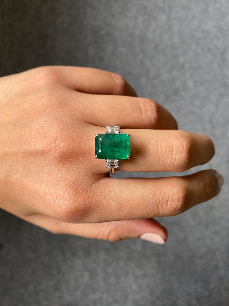 A classic three-stone engagement ring, with a 5.39 carat Zambian Emerald and 0.48 carat VS quality Emerald cut Diamond side stones. The Zambian Emerald is natural, not treated - it is transparent with a beautiful vivid green color and luster. The