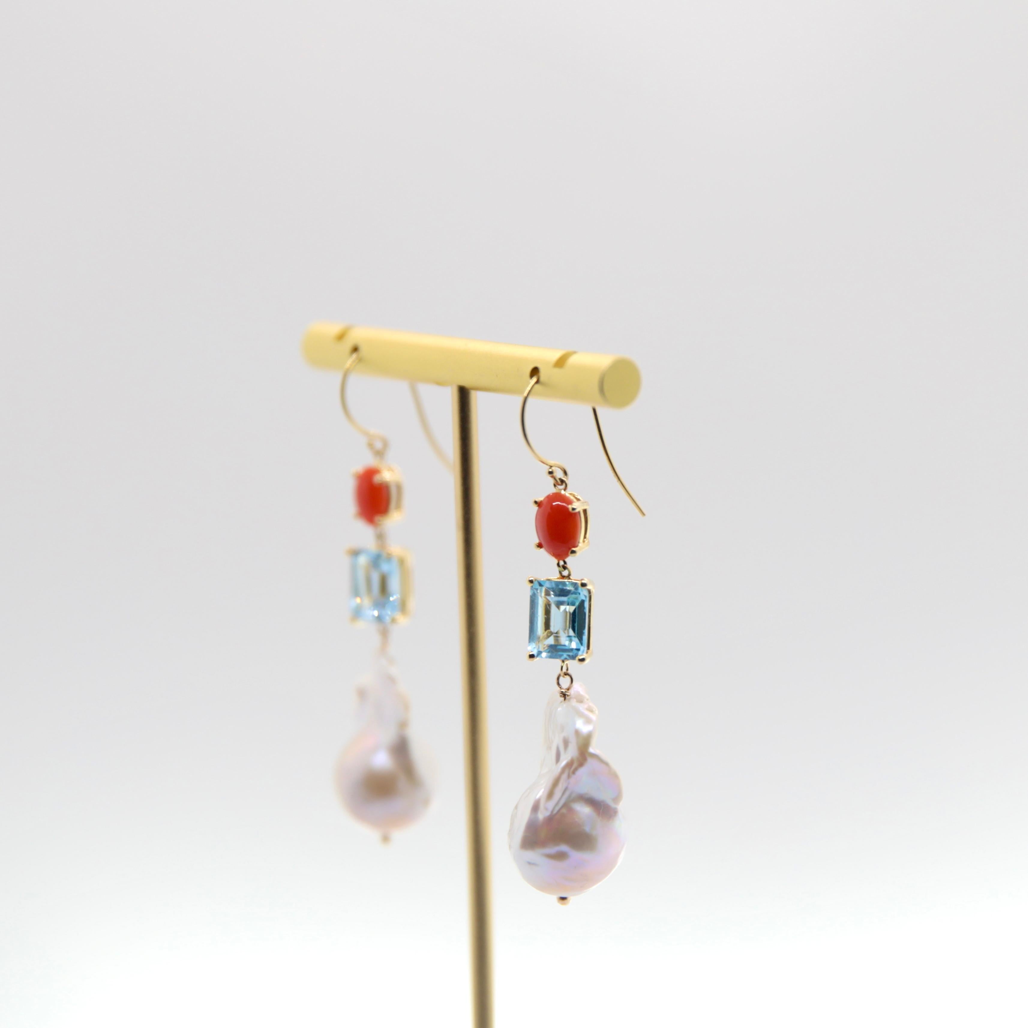 - Suspended in a 14k yellow gold fish hook

- 6x4 mm coral set in a 4 prong setting 

- 9 x 7 mm emerald cut blue tourmaline; approx 2.70 ct / each: 5.40 carat total weight.
   
- Set in a 14k yellow gold, 4 prong basket setting

Blue Tourmaline is
