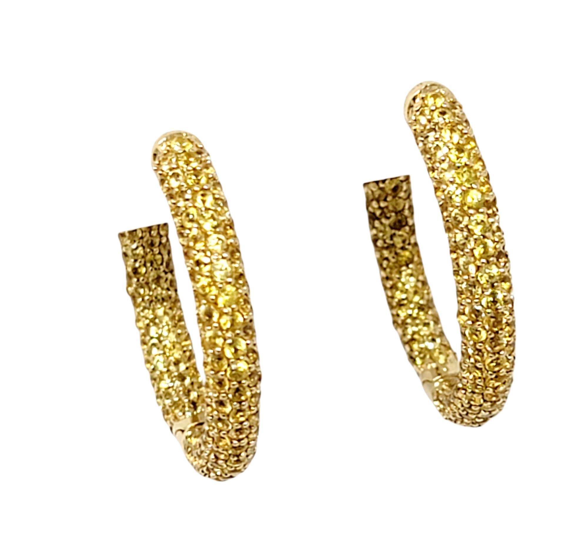 Simply stunning 14 karat yellow gold and yellow sapphire pave hoop earrings. Arranged in a unique inside/outside setting, the stones are positioned to catch the light from different angles, making your lobes absolutely glow. 
These are earrings for