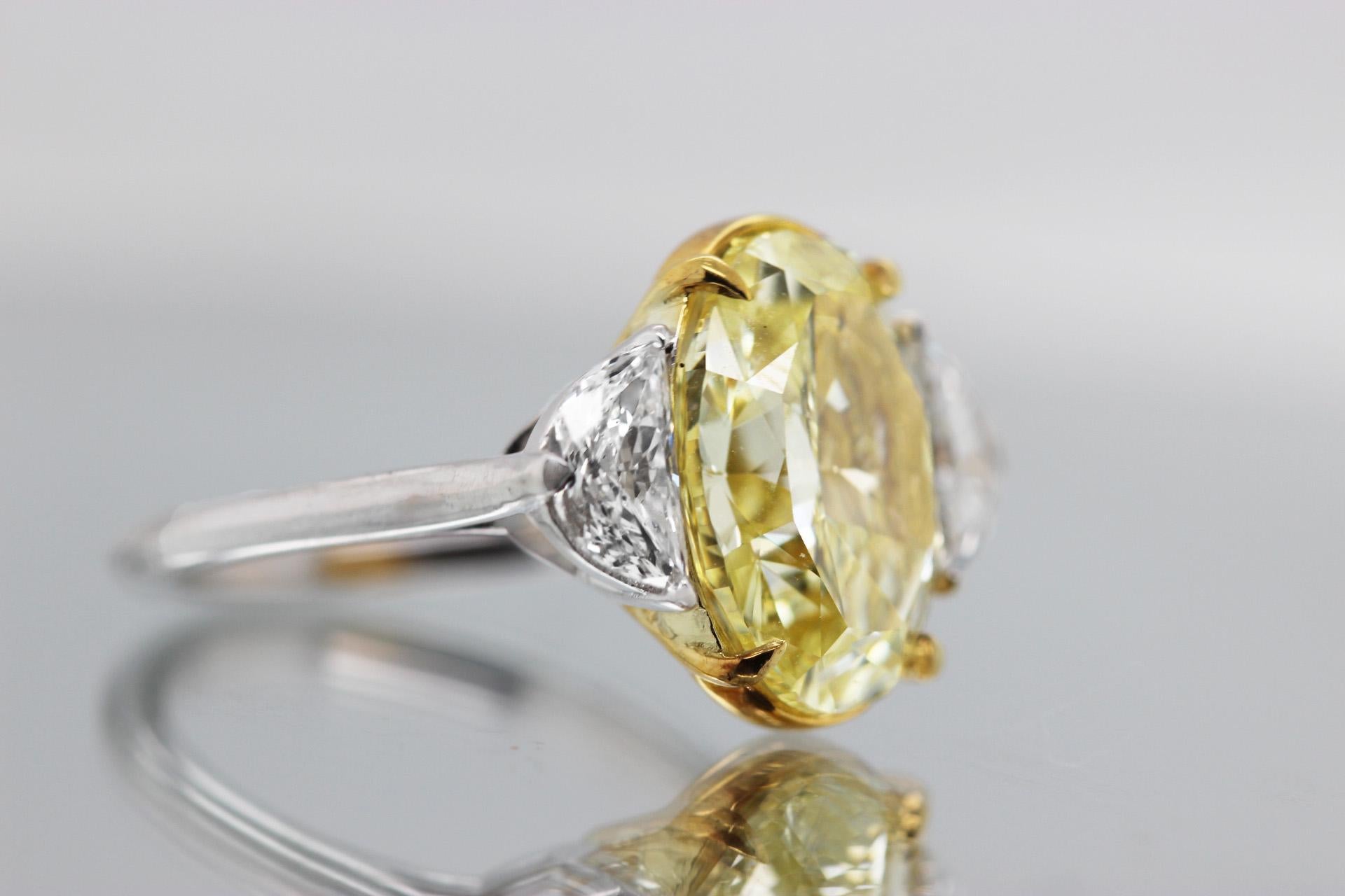 Bague de fiançailles à trois pierres avec un diamant central de 5,40 carats, certifié par le GIA, et deux pierres latérales en forme de demi-lune (0,92 TCW).  Diamant de taille ovale de couleur naturelle jaune fantaisie et de pureté VS1 serti sur or