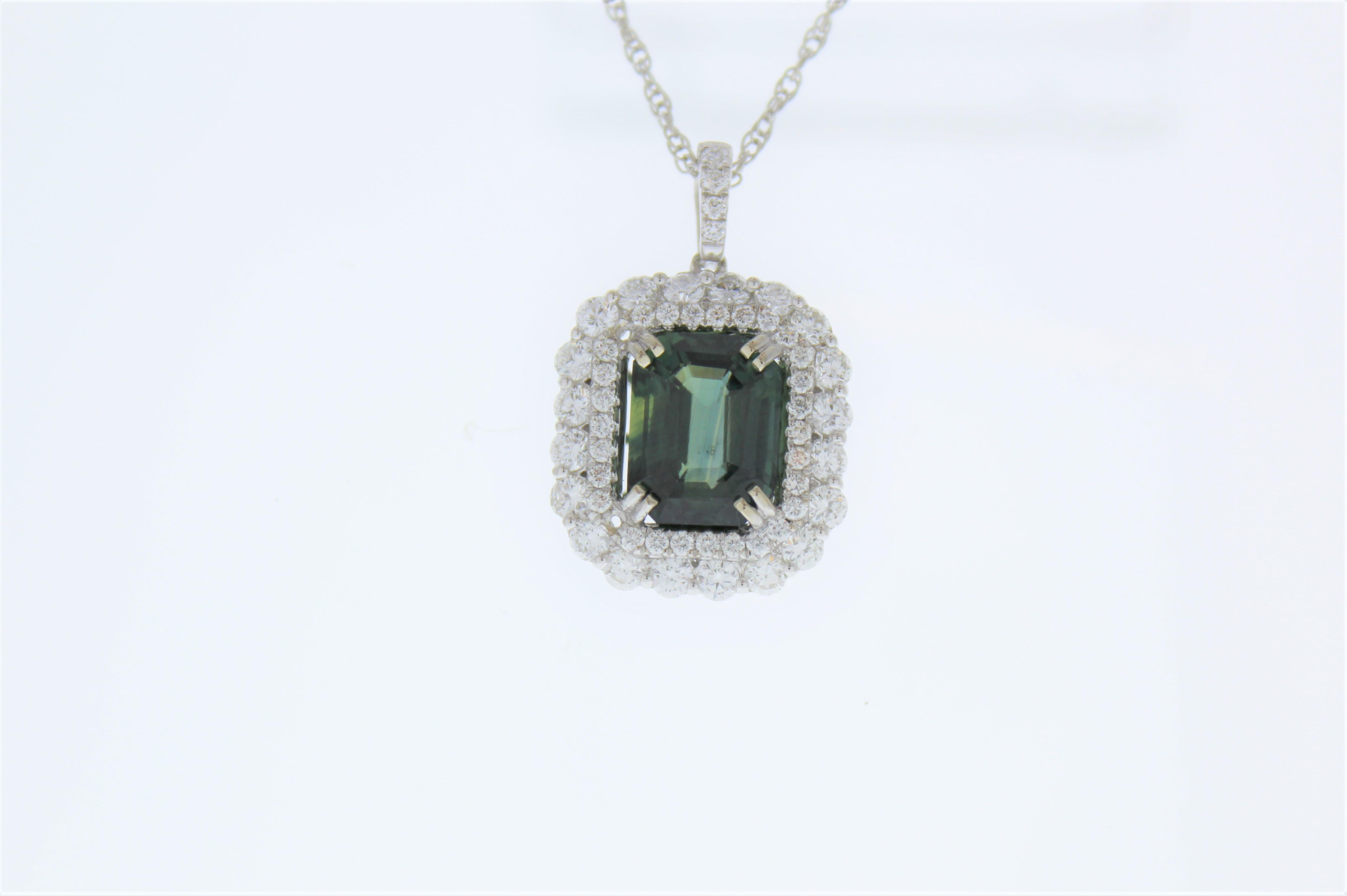 Finish your look with a touch of elegance wearing this gorgeous pendant. One 5.45 carat emerald cut bluish-green sapphire takes center stage in rich white gold accented prongs and is surrounded by round brilliant cut diamonds that are also set on