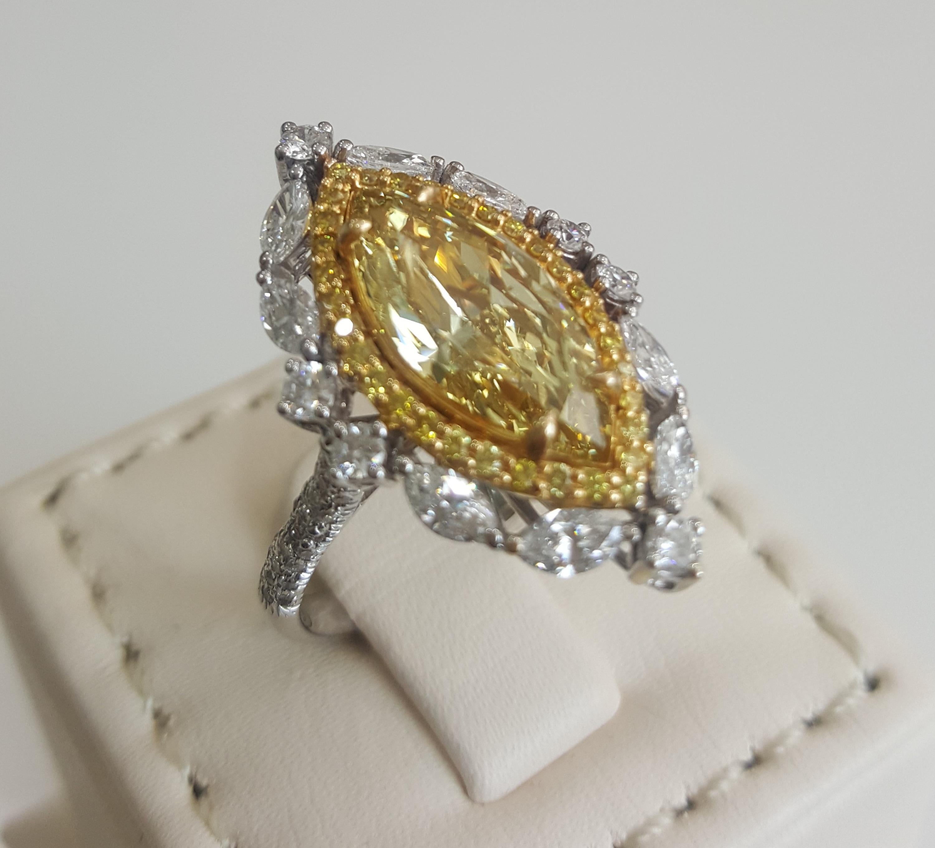 An attractive natural yellow and white diamond ring features a natural yellow marquise shape diamond in the center weighing 4.01 carat with SI clarity encircled with a row of small yellow diamonds weighing 0.23 carat and another row of white