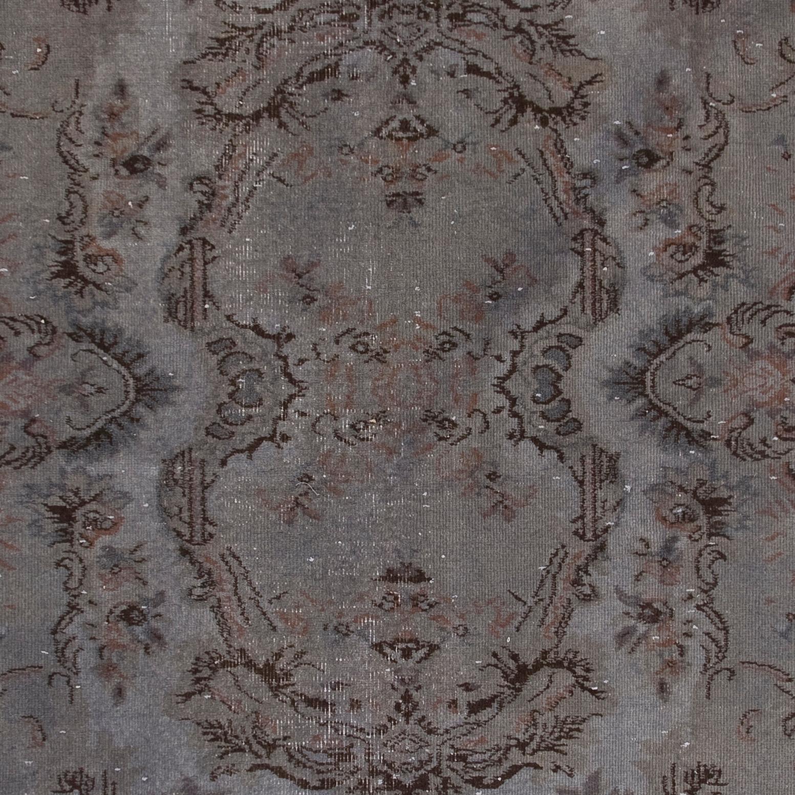 A French-Aubusson inspired vintage hand-knotted Turkish rug over-dyed in gray color. The rug features a design of a central floral cartouche, romantic cabbage roses, bold leafy motifs as well as a laurel border. It is finely hand-knotted with low
