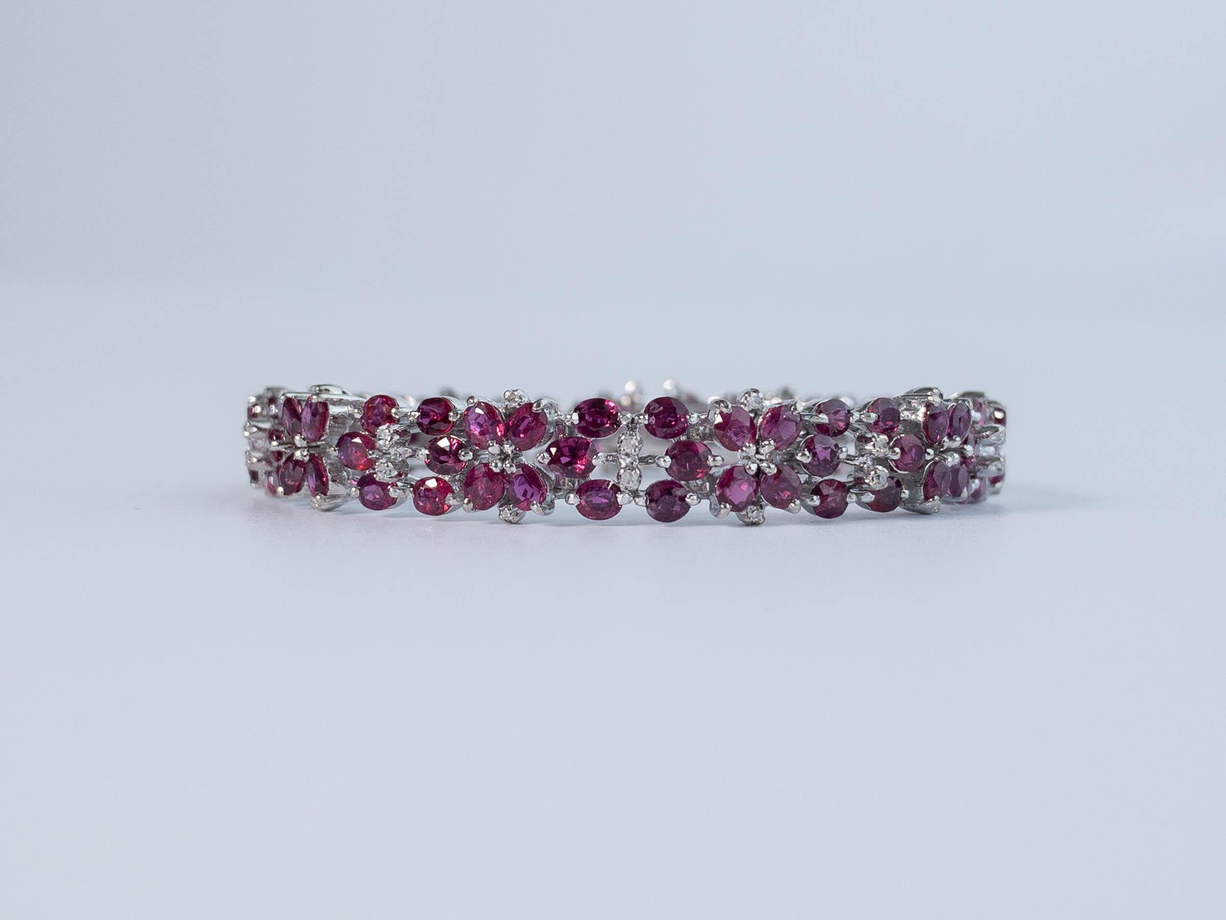 This sweet vintage ruby and white gold bracelet displays a lovely floral pattern. A total of 110 oval shaped rubies are clustered together in a repeating pattern of flowers. Set in white gold, this bracelet is sprinkled throughout with white baby
