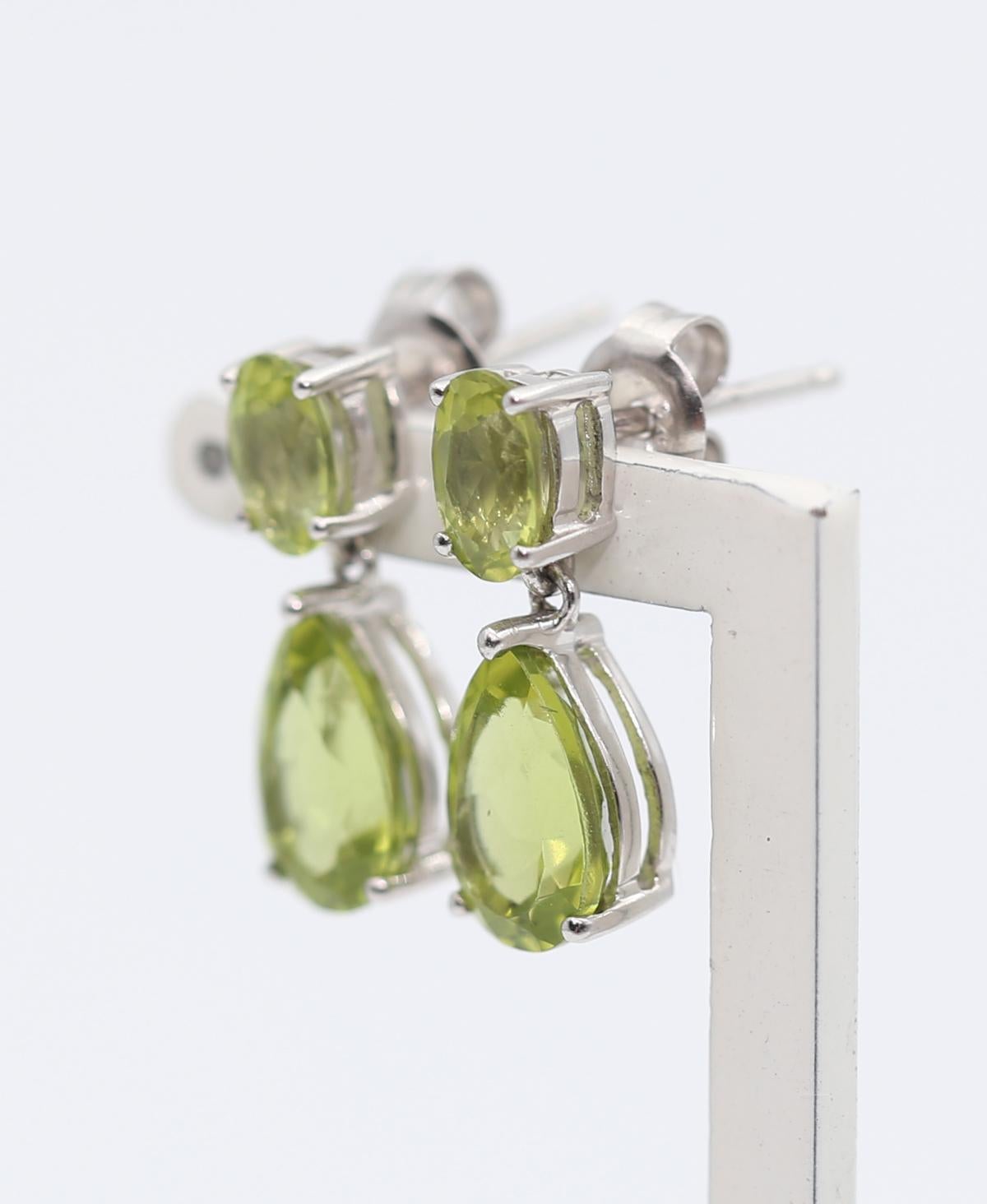 A beautiful pair of 5.50 Carat Peridot drop shapes. Suspended from two oval and pear-shaped Peridot set in White Gold. Vibrant color and relatively massive stones demand attention whenever and wherever it’s worn. The bottom stone is not rigidly