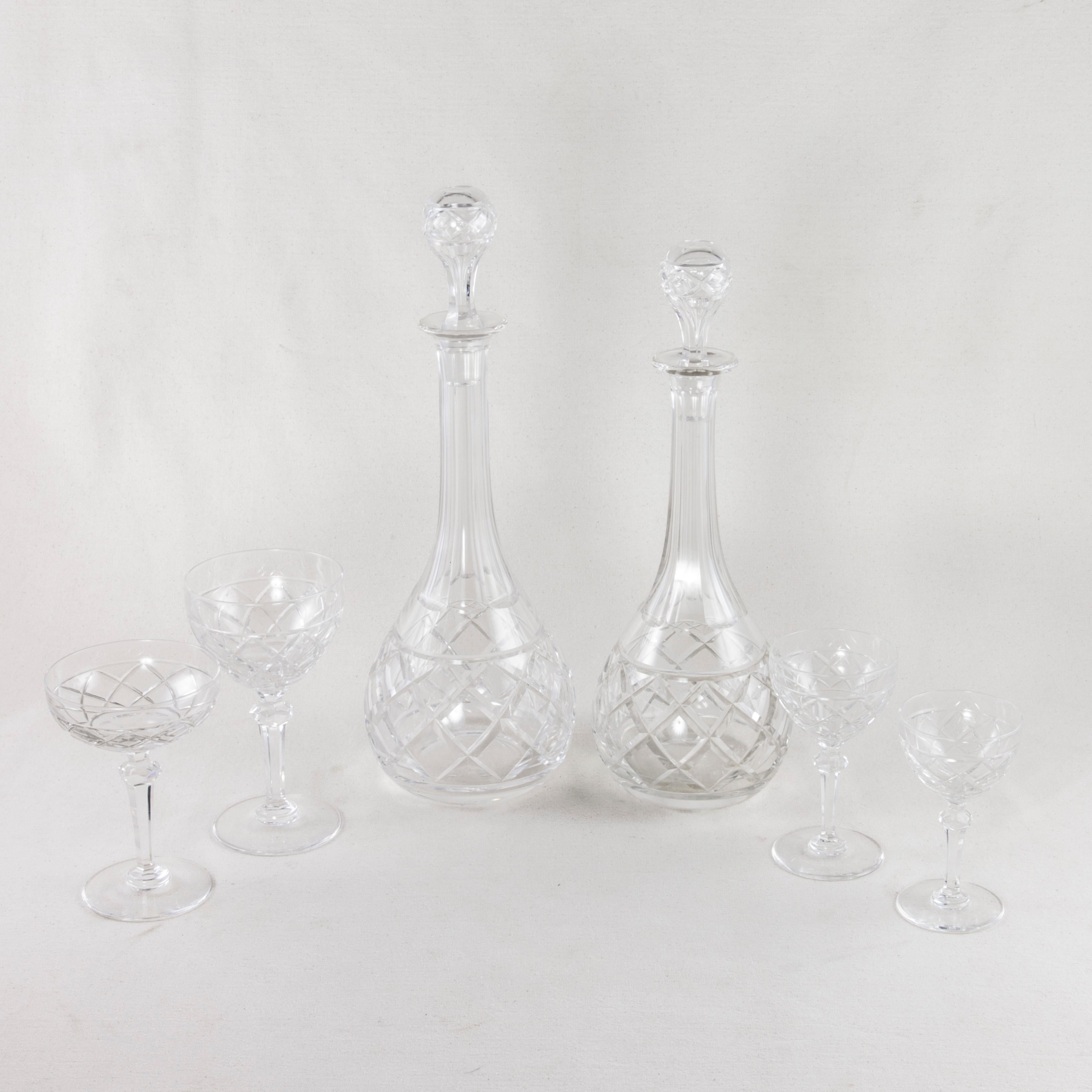 This 55-piece set of early 20th century French Baccarat cut crystal glassware features four different sizes of glasses: twelve champagne, ten red wine, ten white wine, and ten liqueur. Included are four decanters with stoppers, a pair of vases, and