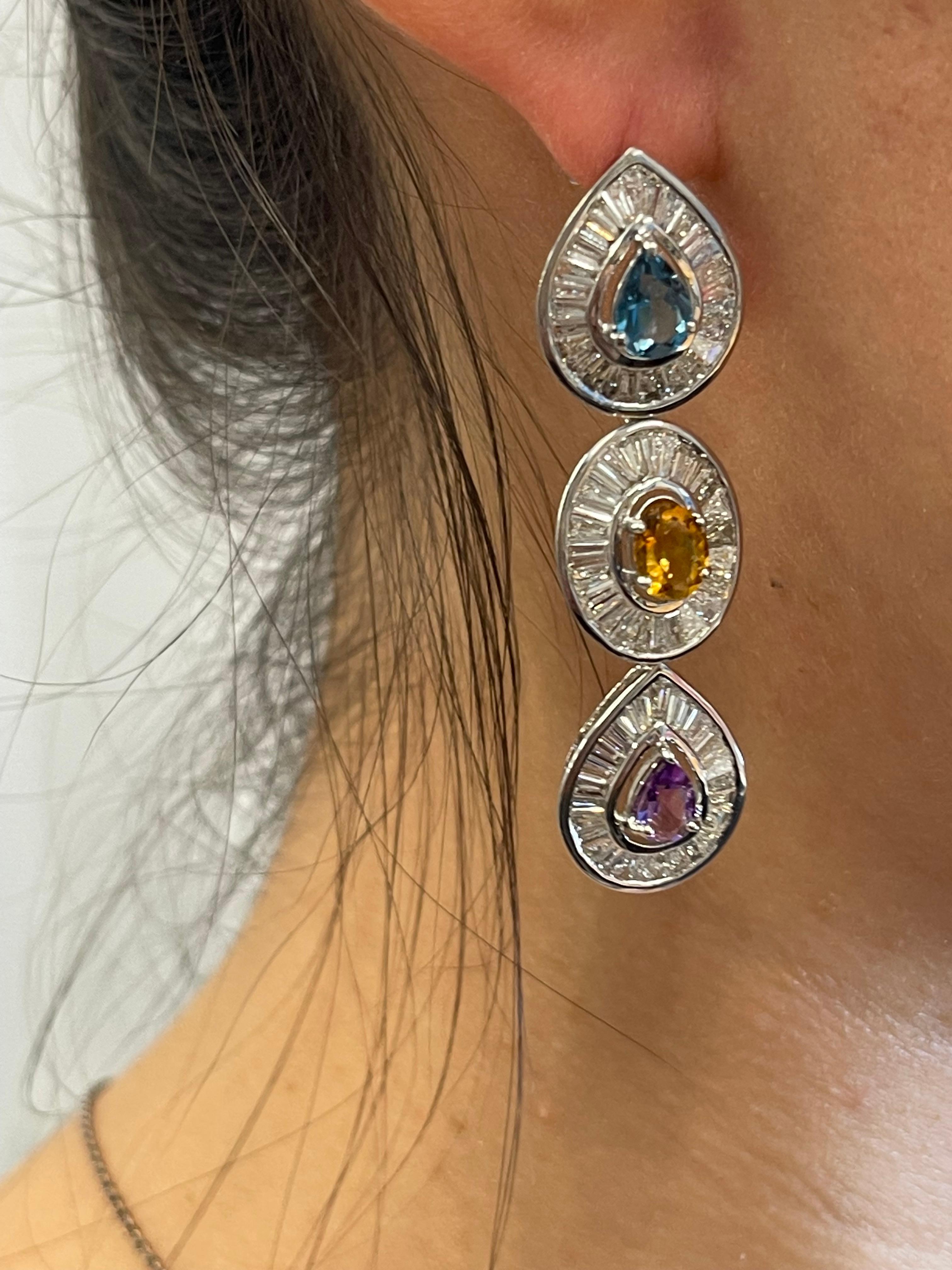 These are natural multi-colored sapphire earrings that feature a bevy of colors coupled with contrasting white brilliant diamonds. Mixed shaped colorful sapphires total 5.50 carats. This pair of stunning drop earrings makes a statement of incredible