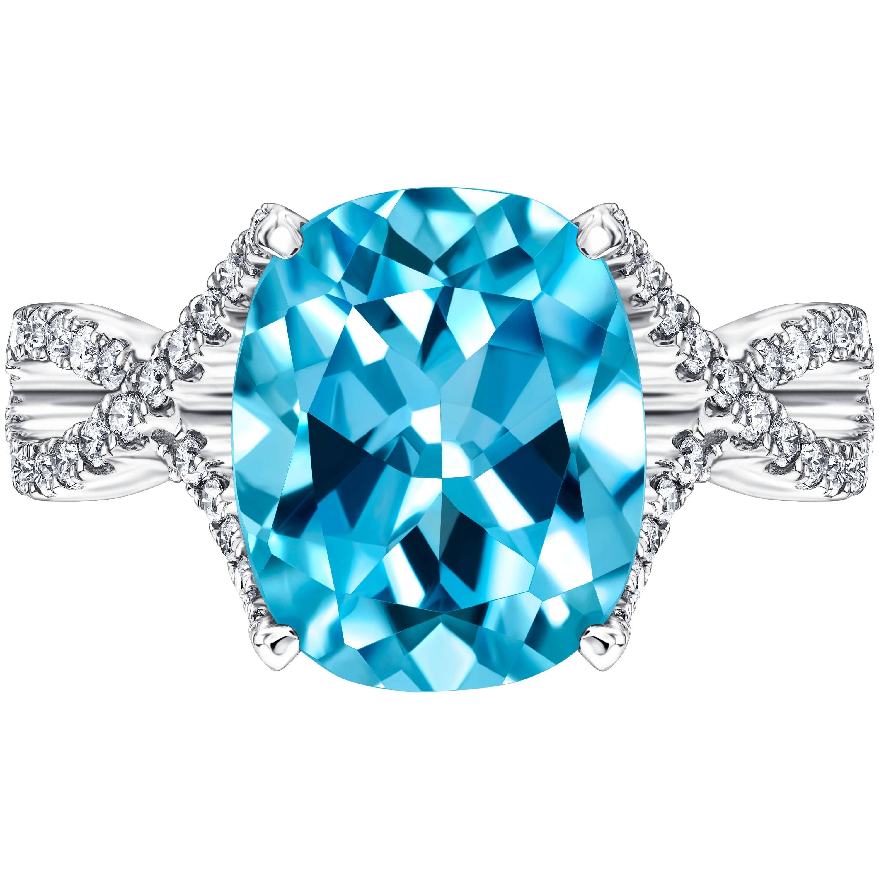 This Stunning 5.50ct Cushion Cut Blue Topaz Engagement Ring set in 18ct White Gold with Four Claws. Featuring an intertwined Ring Shank set with 0.66ct H-SI Pave set Diamonds. This Ring has a total weight of 6.16 carats. With a quality grading of