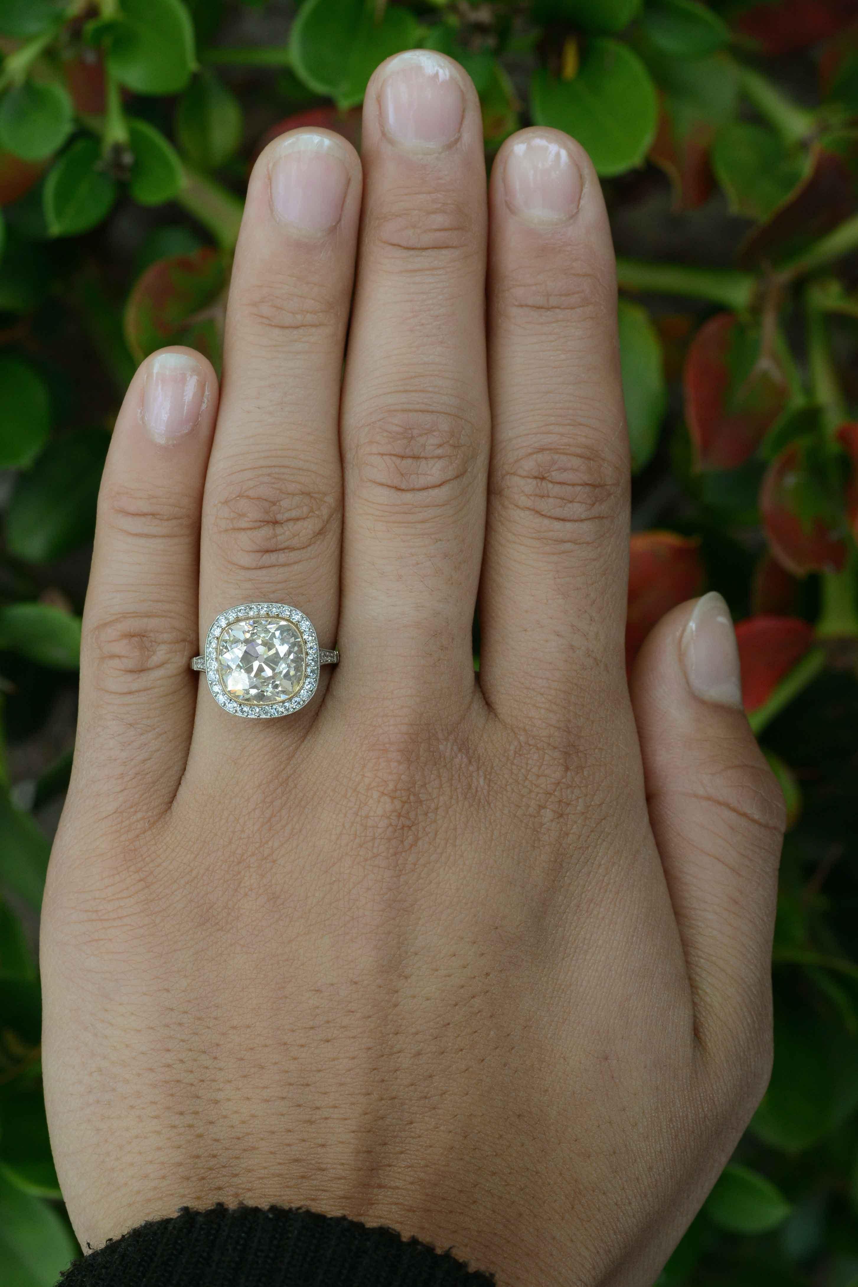 Centering on a massive, 5.51 Carat antique yellow diamond, this Edwardian style engagement ring was hand fabricated in platinum using the original gems from a well-loved but worn antique engagement ring. The chunky facets and high crown of this old,