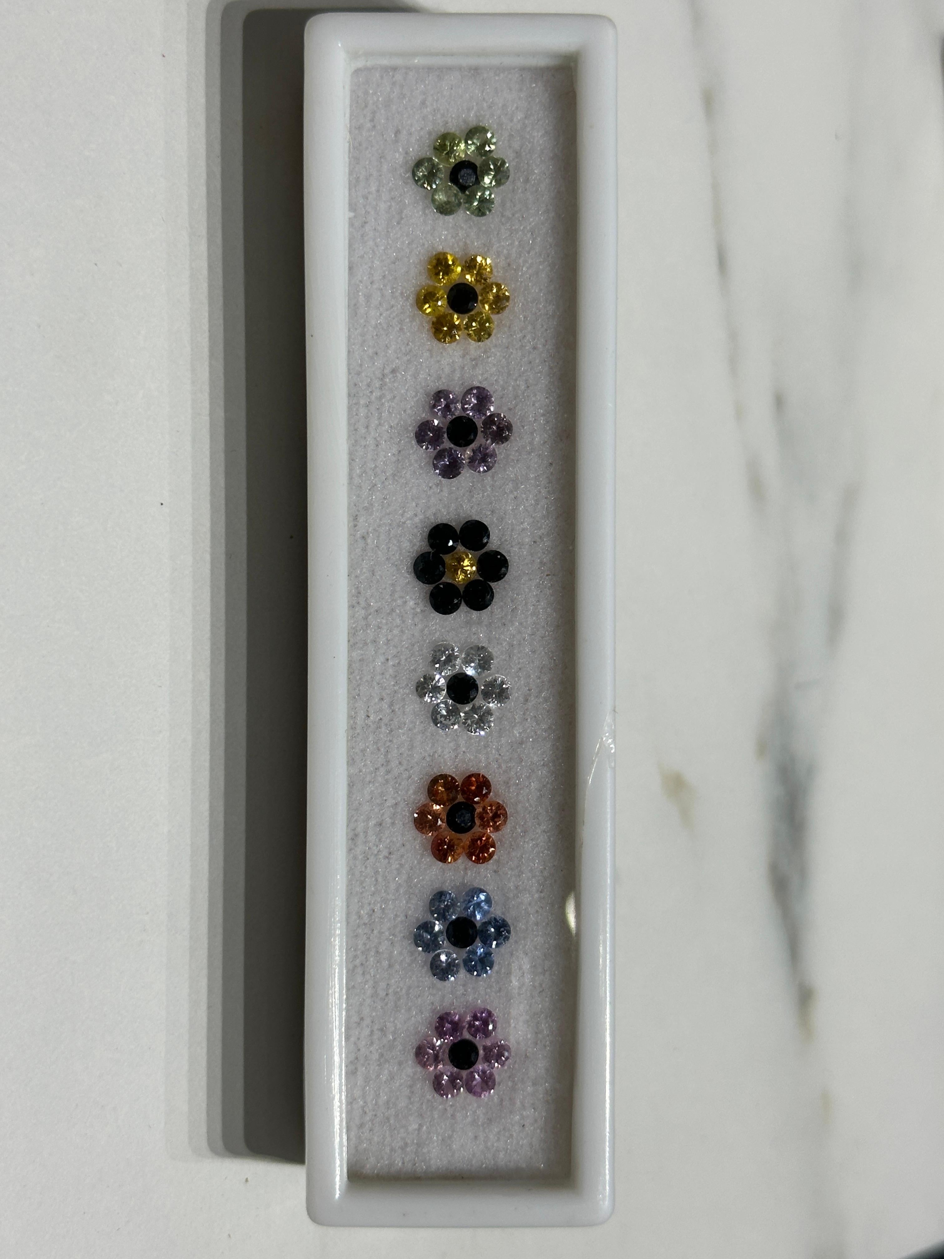 A wonderful lot of 56 2.7mm Natural Fancy Sapphires that lay in an orderly floral formation.
Though they are quite tiny, these diamond-cut sapphires are rich in color and show a full and lively brilliance.
The total weight of this lot amounts to