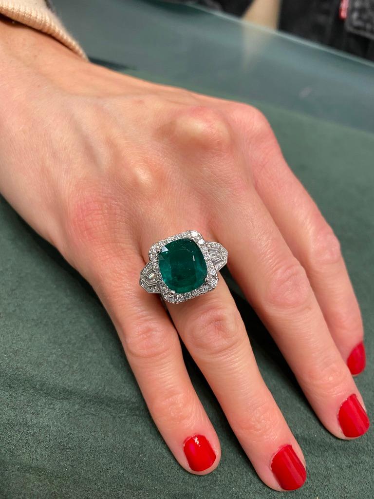 Exquisite emerald and diamond three stone / halo ring. 
5.53 carat cushion emerald. Complimented with 66 round brilliant diamonds and 2 shield diamonds, approximately G/H color and VS clarity. 6.72ct total gemstone weight, in 18k white gold with