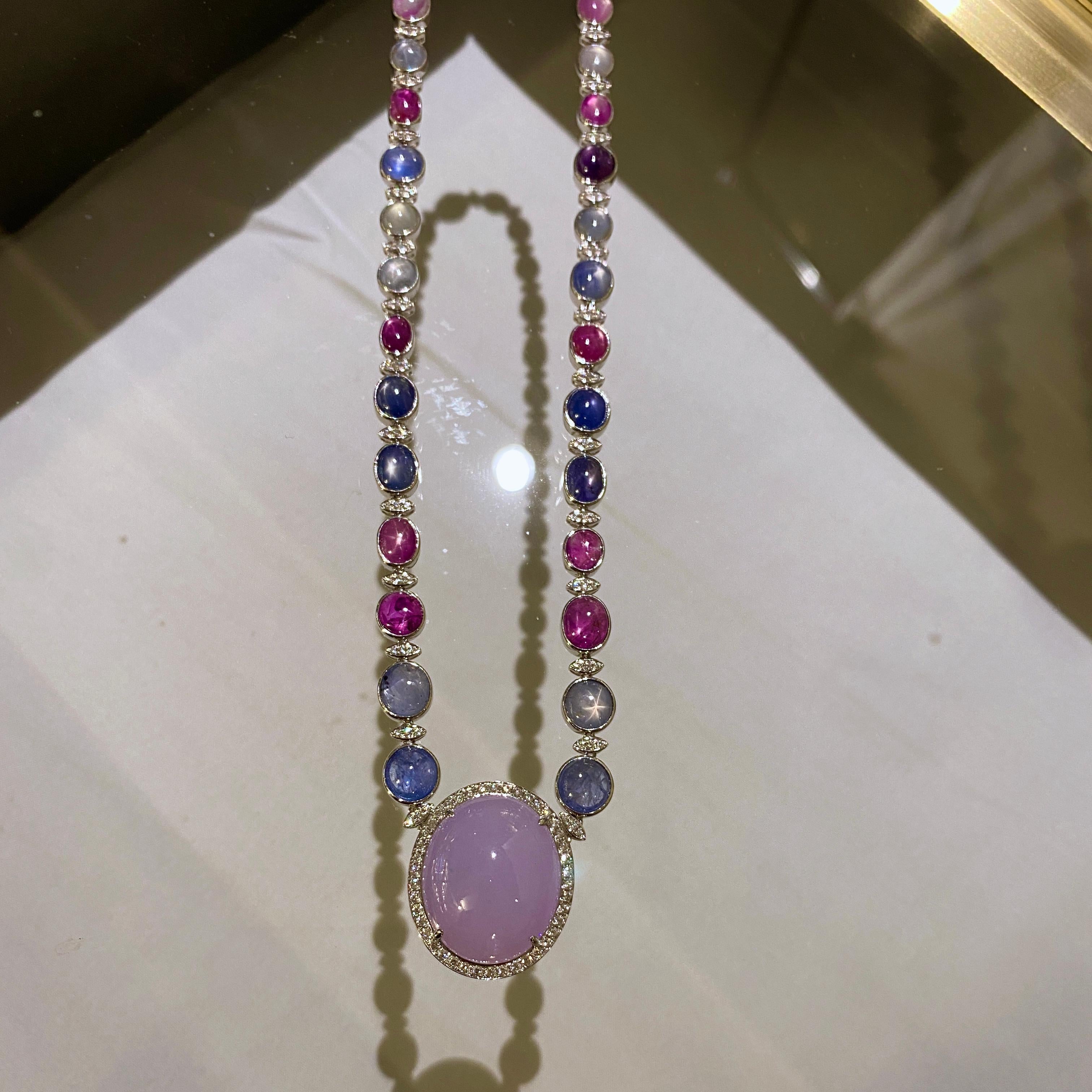 Questa collana di grande effetto è dotata di ben 55,36 carati di Zaffiro Stellato e di un enorme Cabochon di Giadeite di tipo A. La giadeite è circondata da un pavé di diamanti e poi collegata alla collana di zaffiri a stella. Lo Zaffiro Stella