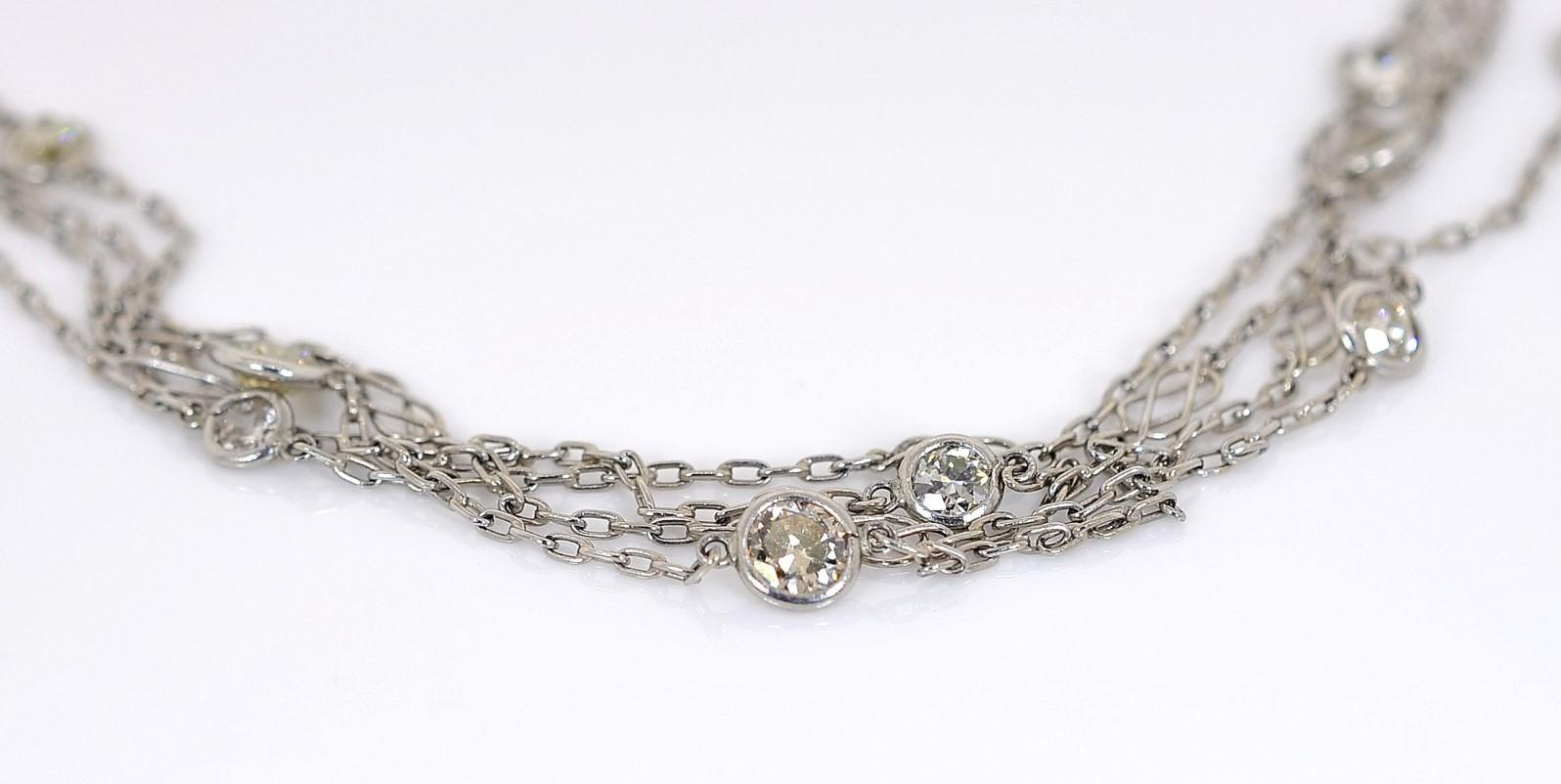 Hand-made of platinum this lovely chain necklace is interspersed with twenty five (25) Old sparkling and Round Brilliant cut diamonds, totaling 5.54 carat.  The bezel set diamonds vary in size and color creating an interesting mix.  Filigree swirl