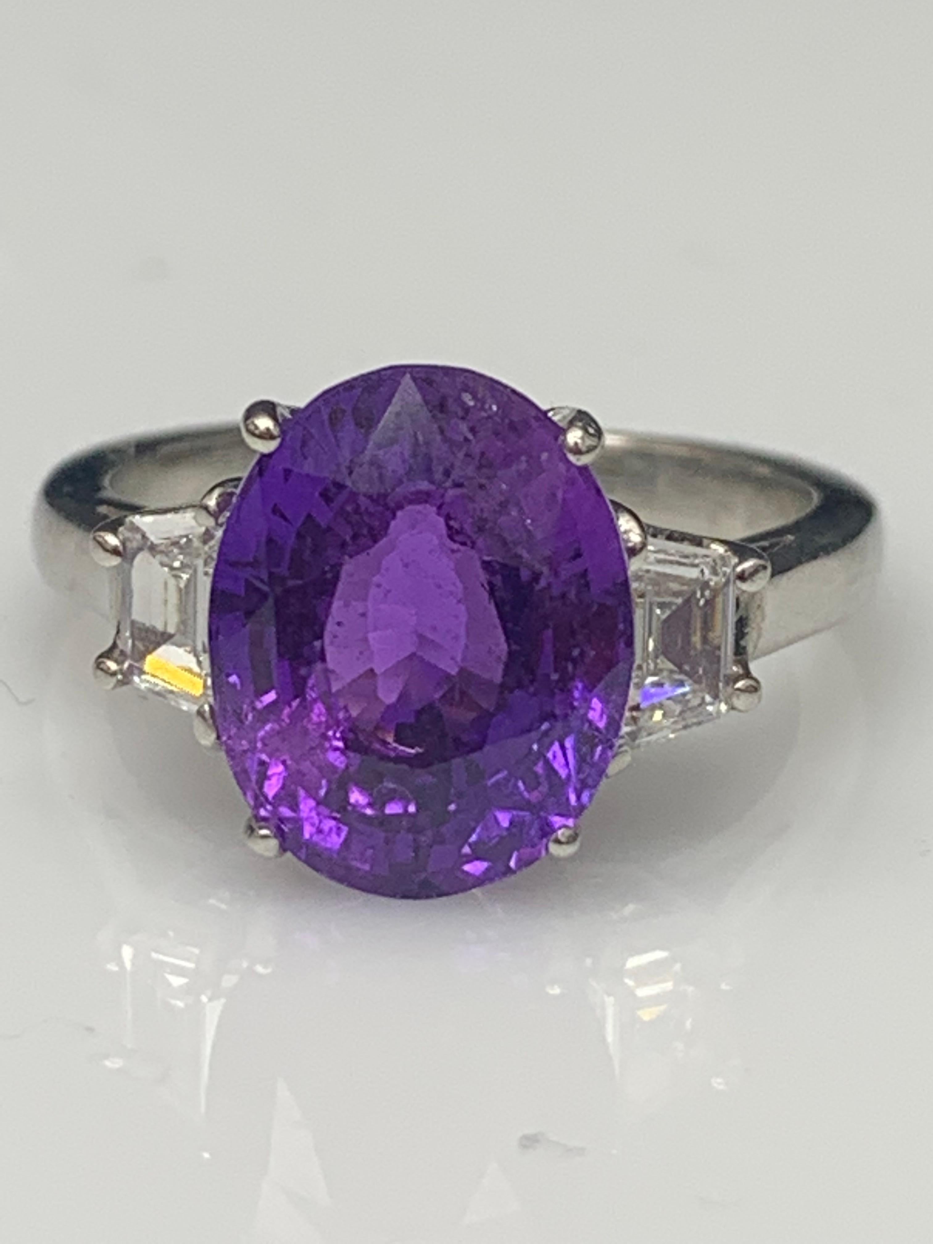 Showcases an Oval cut , Vibrant color Purple Sapphire weighing 5.56 carats, flanked by two brilliant cut trapezoid diamonds weighing 0.60 carats total. Elegantly set in a polished platinum composition.