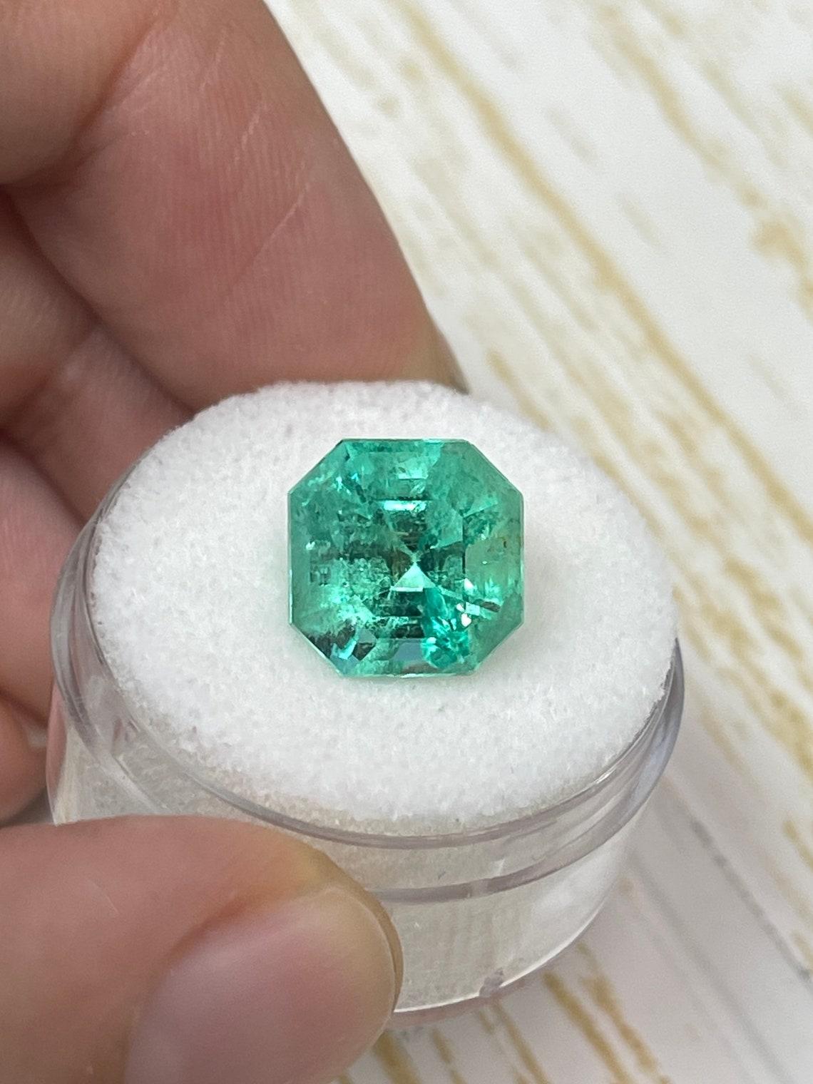 Stone: Emerald
Weight: 5.56-carats
Shape: Asscher Cut
Clarity: Transparent
Luster: Very Good
Color: Medium Yellowish Green
Measurements: 10.69mm x 10.62mm x 8.39mm
Geographic Origin: Colombia
Treatment: Natural, Oiling

Comments: Due to their growth