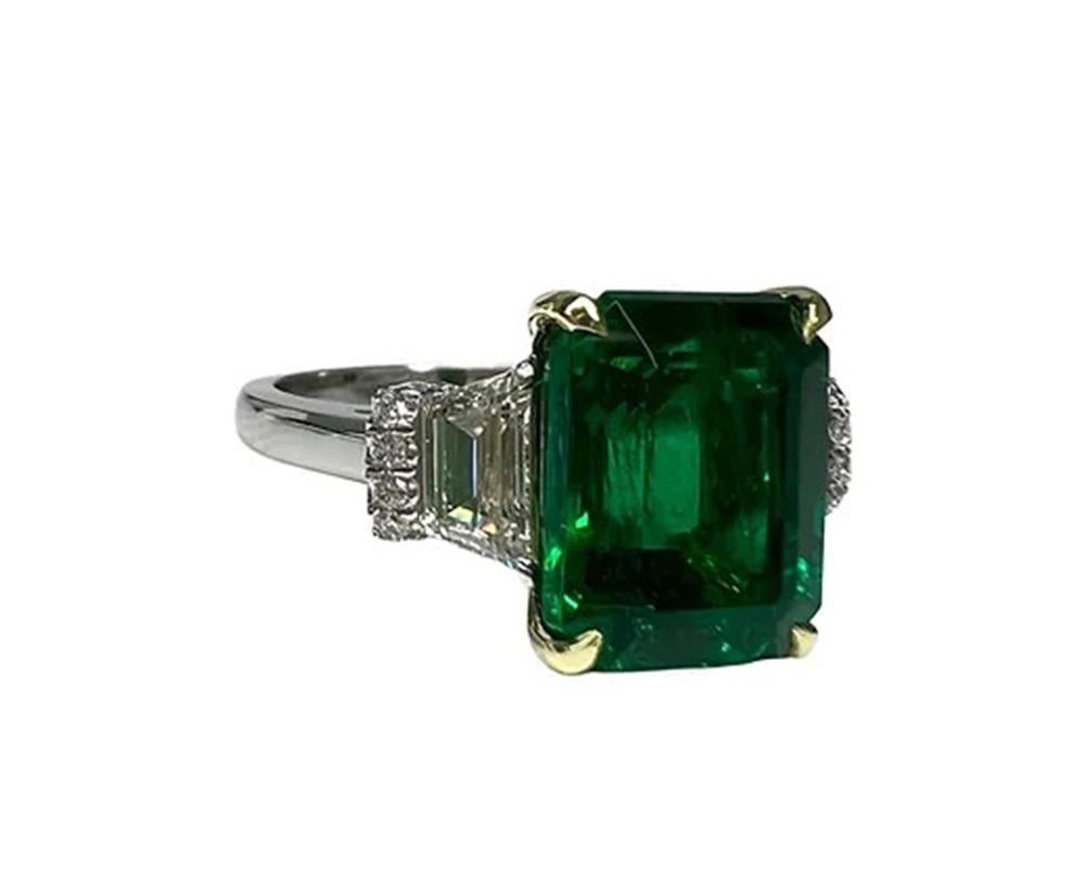 Emerald Weight: 5.57 CTS, Measurements: 11.6 x 9.4 mm, Trapezoid Diamond Weight: 0.91 CT (G-VS), Round Diamond Weight: 0.24 CTS, Metal: Platinum/18K Yellow Gold Basket, Ring Size: 6, Shape: Emerald-Cut, Color: Intense Green, Hardness: 7.5-8,