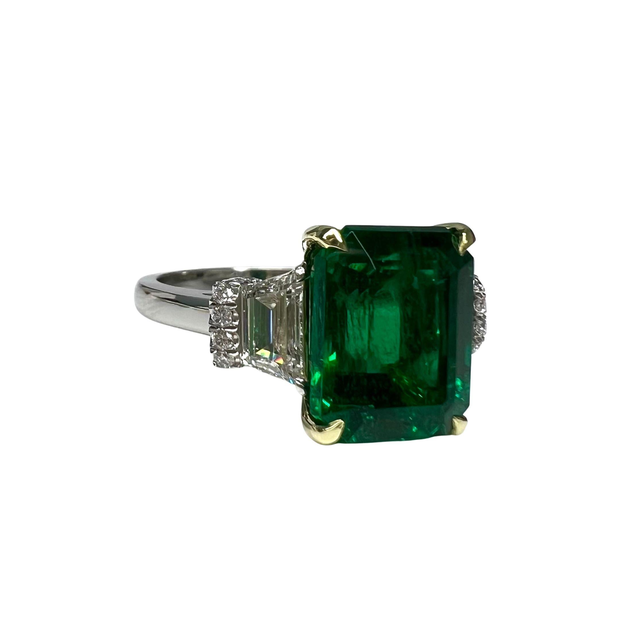 Emerald Weight: 5.57 CTS
Measurements: 11.6 x 9.4 mm
Trapezoid Diamond Weight: 0.91 CT (G-VS)
Round Diamond Weight: 0.24 CTS
Metal: Platinum/18K Yellow Gold Basket
Ring Size: 6
Shape: Emerald-Cut
Color: Intense Green
Hardness: 7.5-8
Birthstone: May