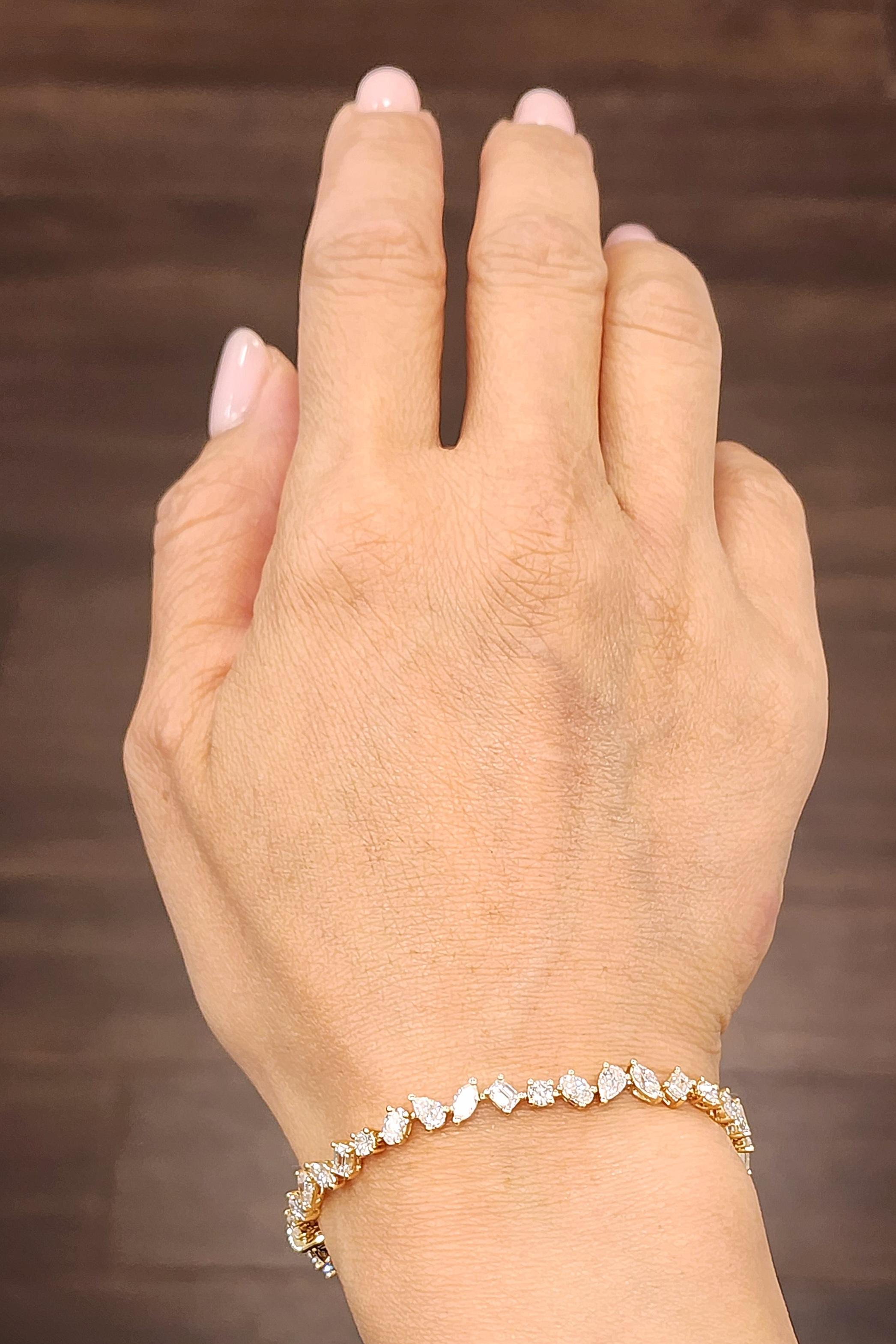 Esta impresionante pulsera de tenis de diamantes de formas mixtas presenta diamantes redondos, marquesas, peras, esmeraldas y óvalos engastados en oro amarillo de 18k. La pulsera presenta 40 diamantes, que ostentan un color F/G y una claridad